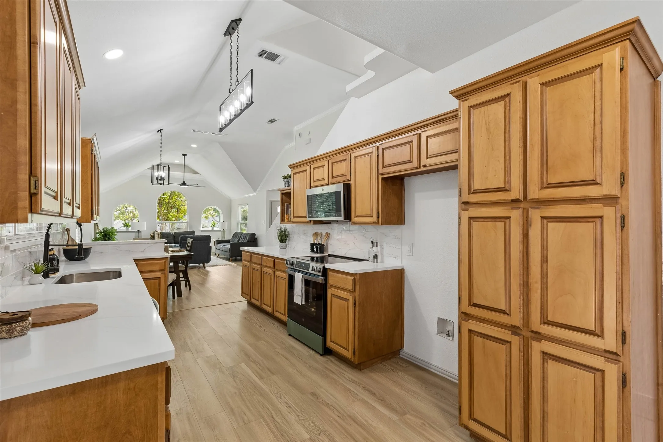 Kitchen featuring wood-finish cabinetry, white countertops, tile backsplash, and stainless steel appliances