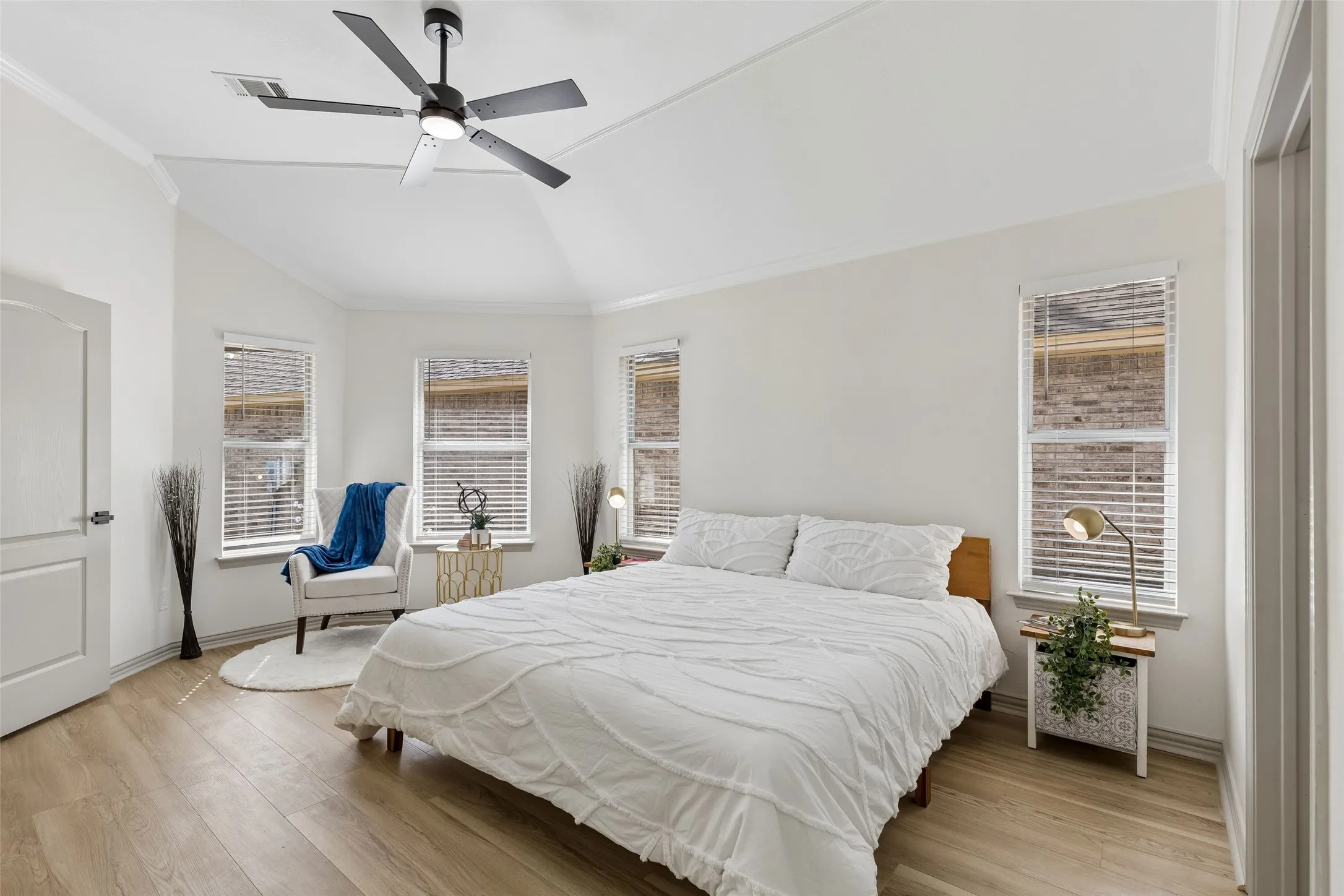 Vaulted ceiling with a black ceiling fan, wood-finish flooring, and multiple windows with blinds