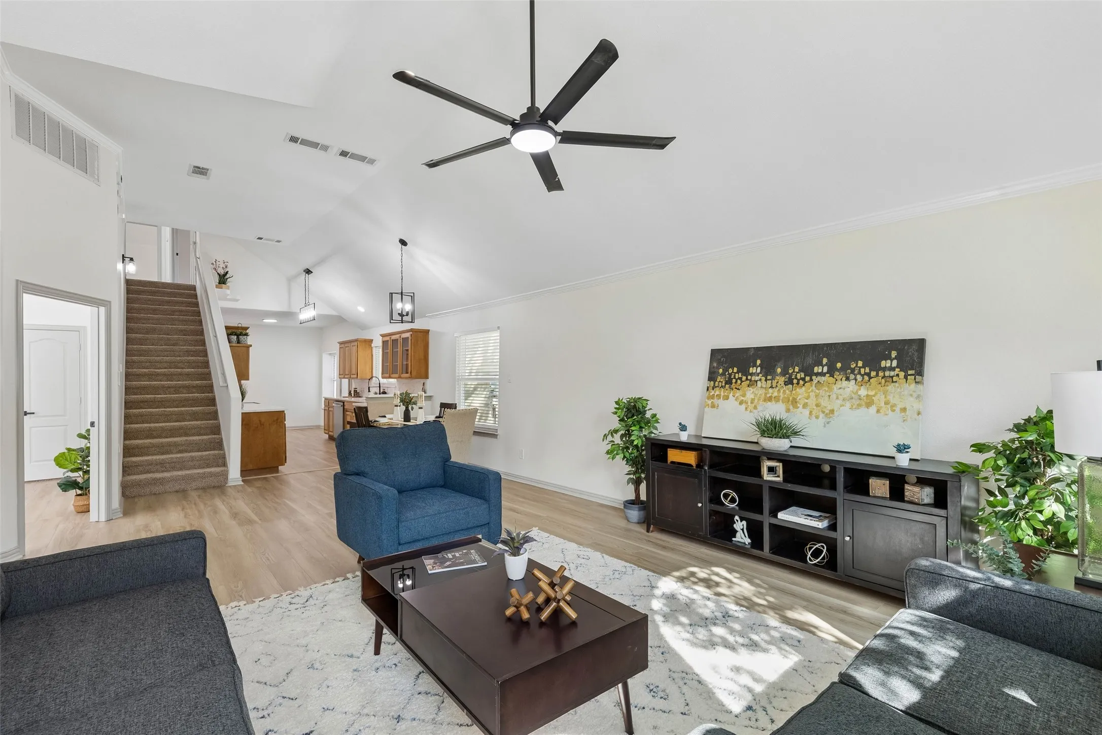Vaulted ceiling with a ceiling fan, wood-finish flooring, and a carpeted staircase