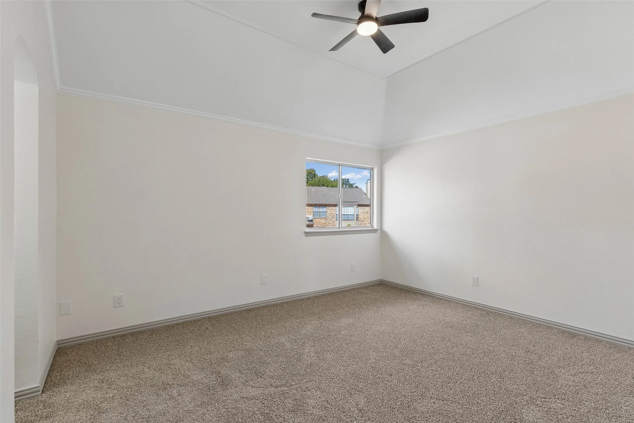 Vaulted ceiling with crown molding, ceiling fan with integrated lighting, carpeted flooring, and a single window