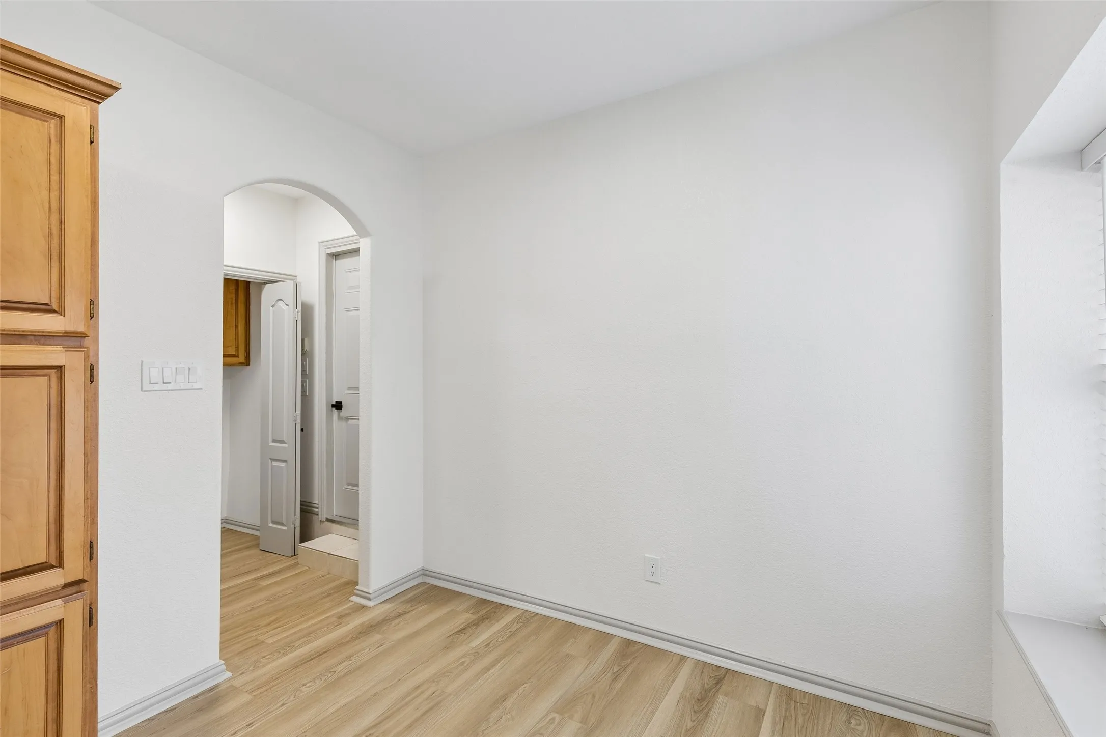 Wood-finish flooring, white walls, and an arched doorway