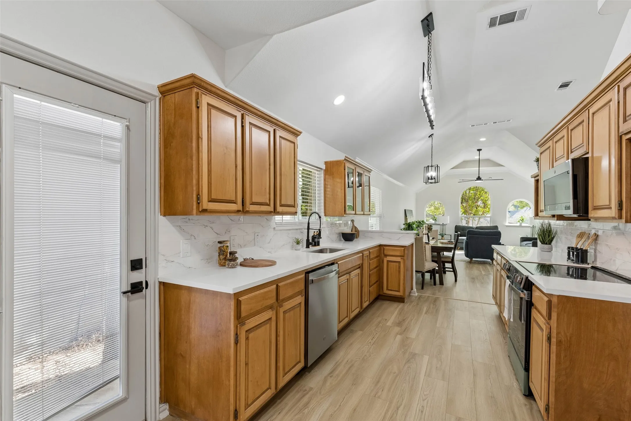 Vaulted ceilings, wood-finish flooring, custom cabinetry, stainless steel appliances, and white countertops
