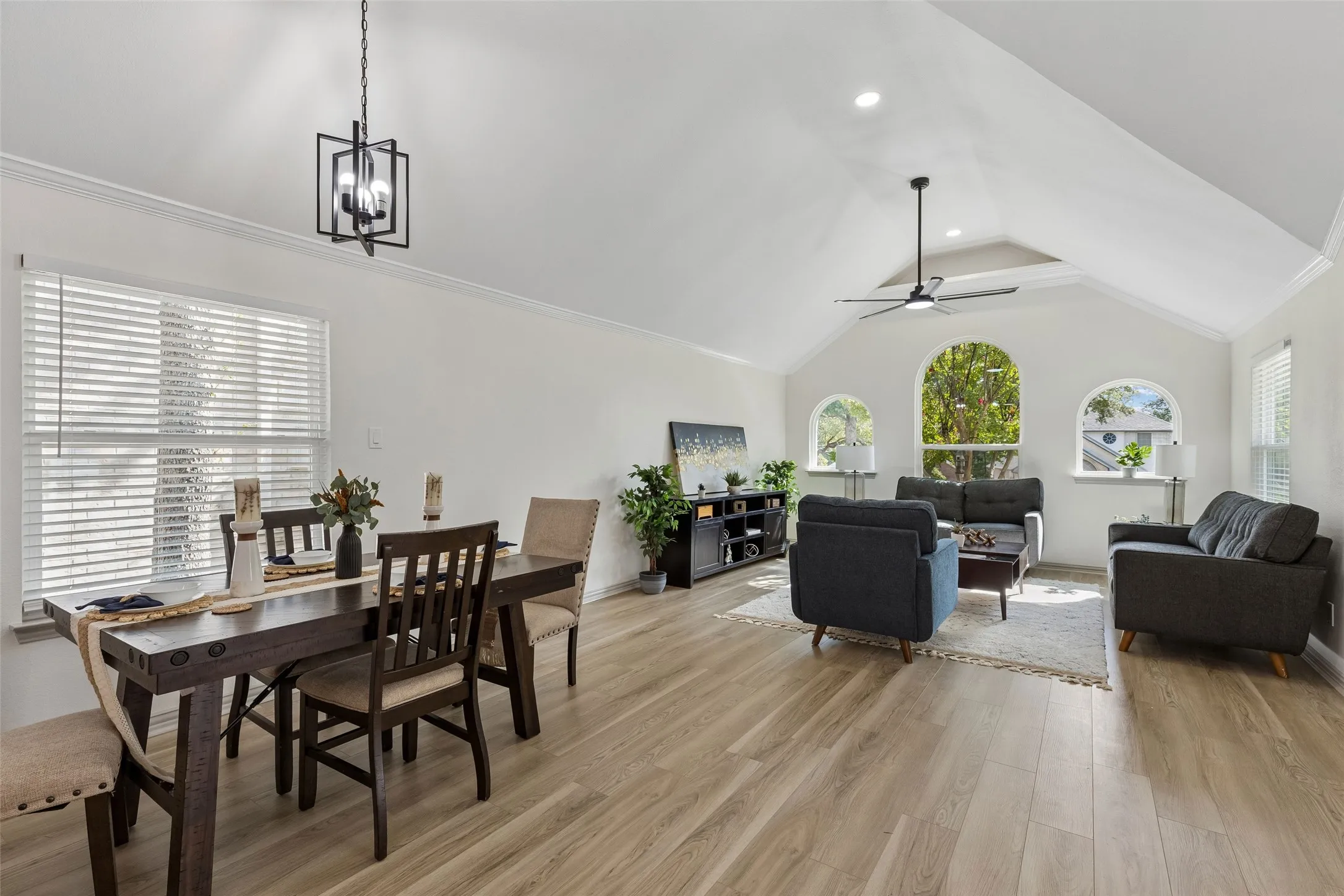 Vaulted ceilings with recessed lighting, wood-finish flooring, three arched windows, and a modern ceiling fan