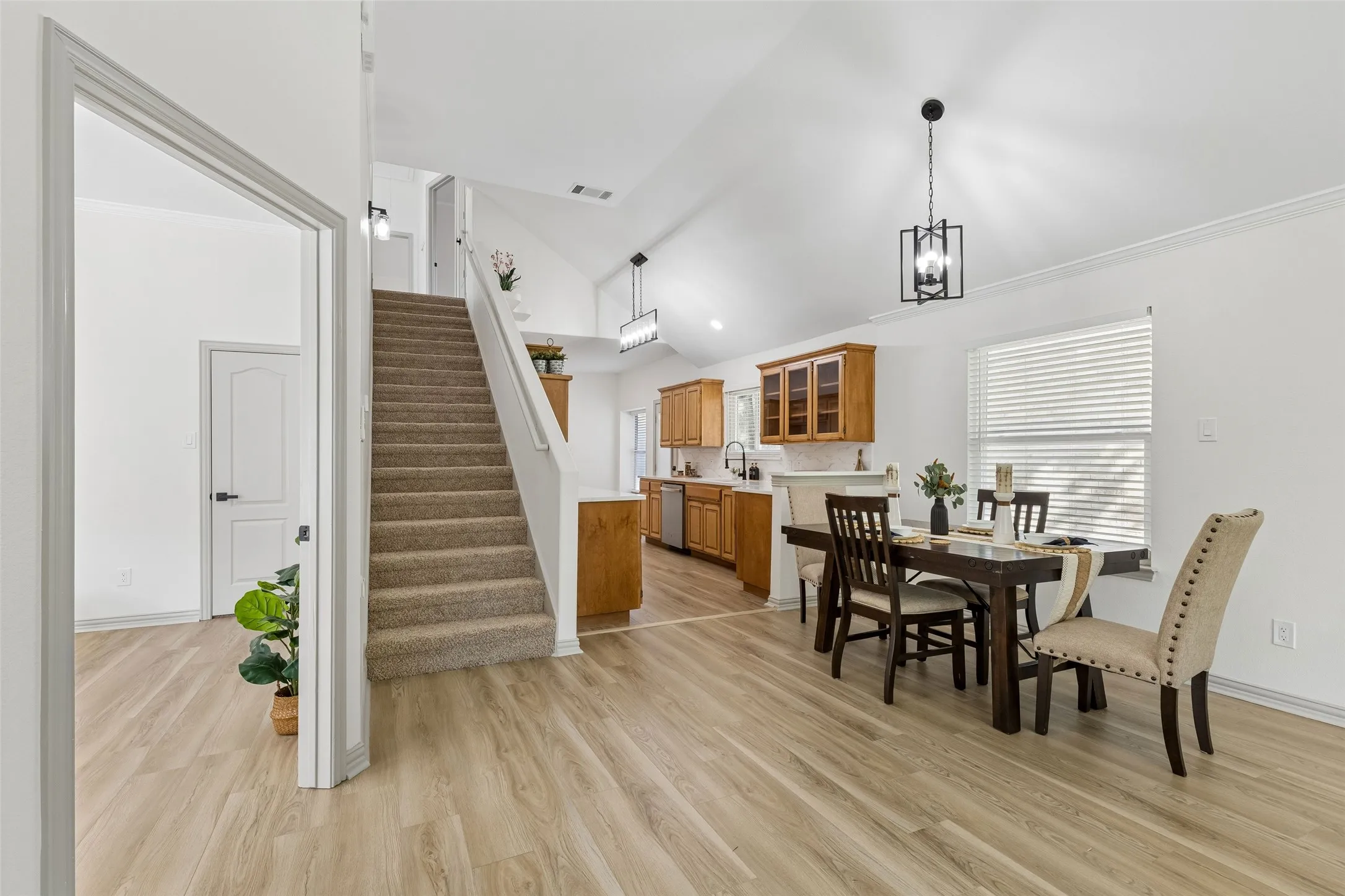 Vaulted ceilings, wood-finish flooring, carpeted staircase, recessed lighting, and kitchen with wood cabinetry