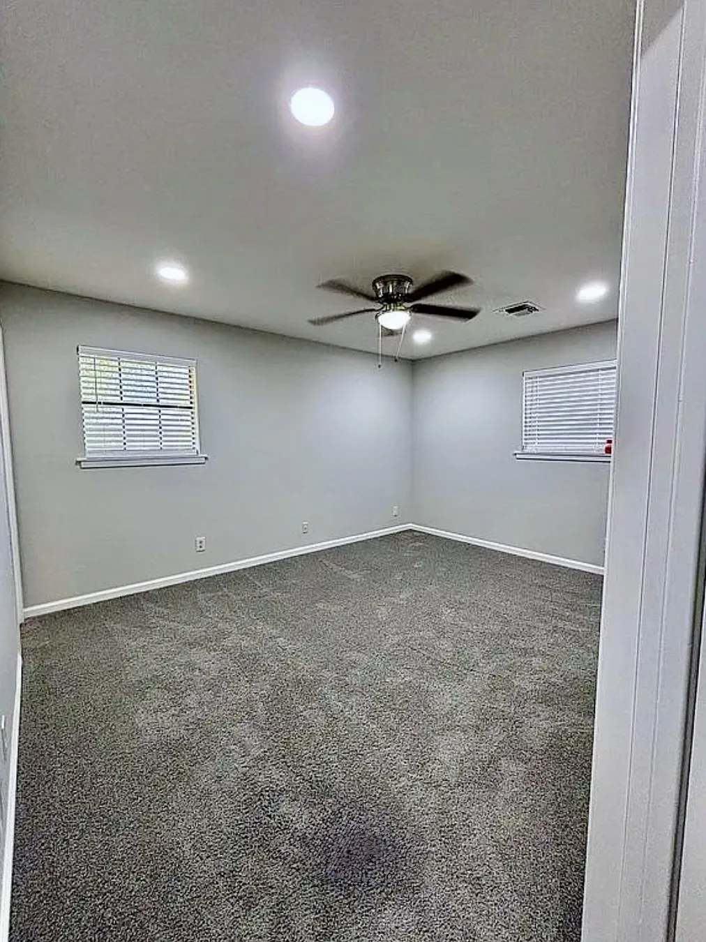 Recessed ceiling lighting, ceiling fan, neutral wall paint, window blinds, and gray carpeting