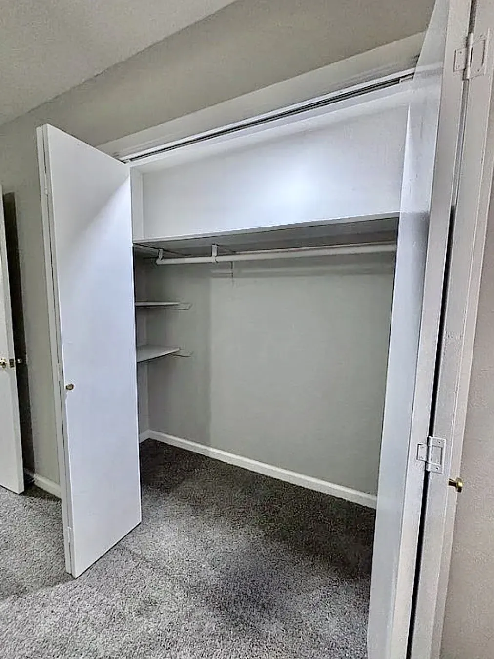 Built-in closet with bi-fold doors, integrated shelving, and hanging rod