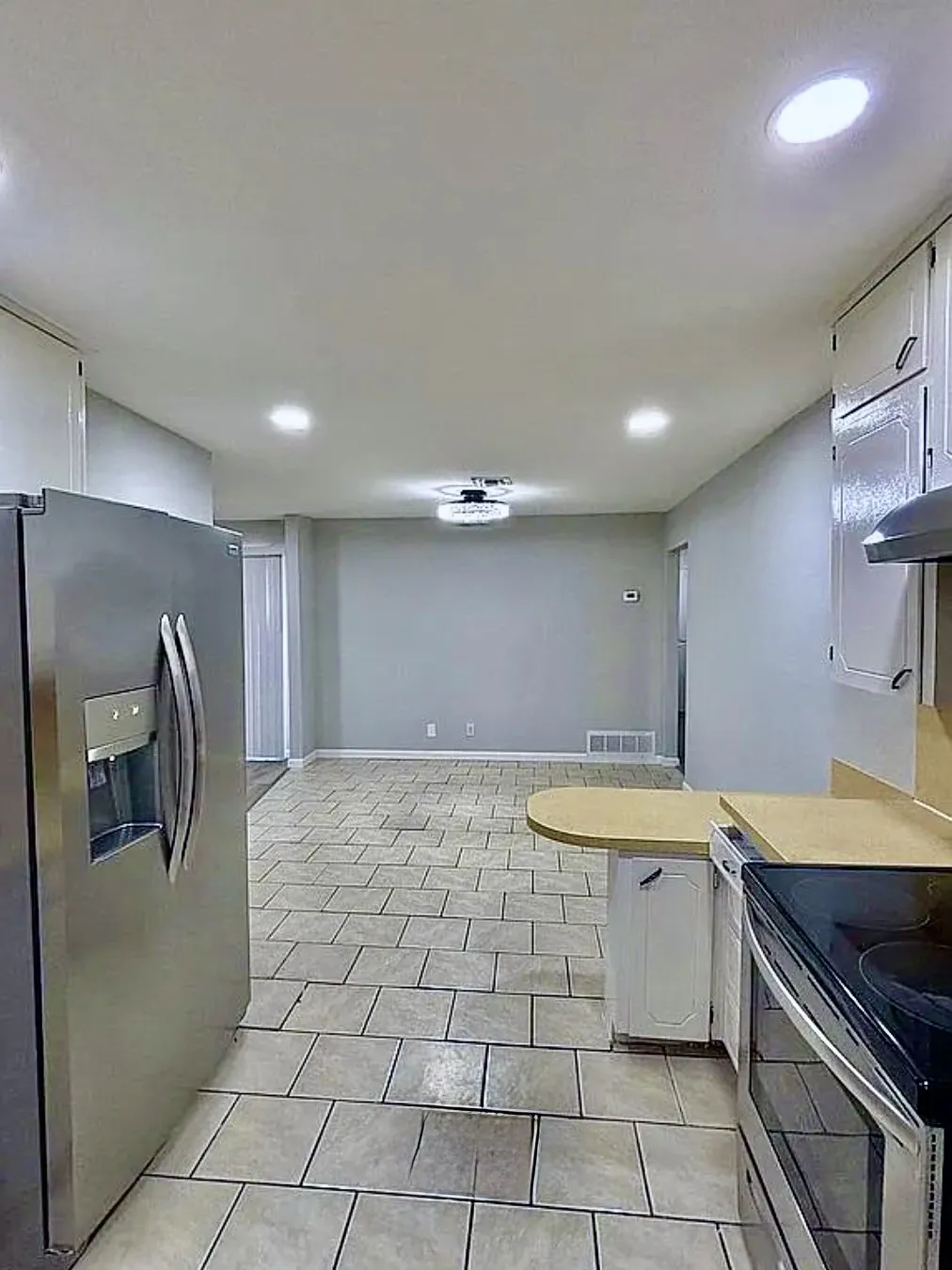 Kitchen featuring tile flooring, white cabinetry, light-toned countertops, and stainless steel appliances