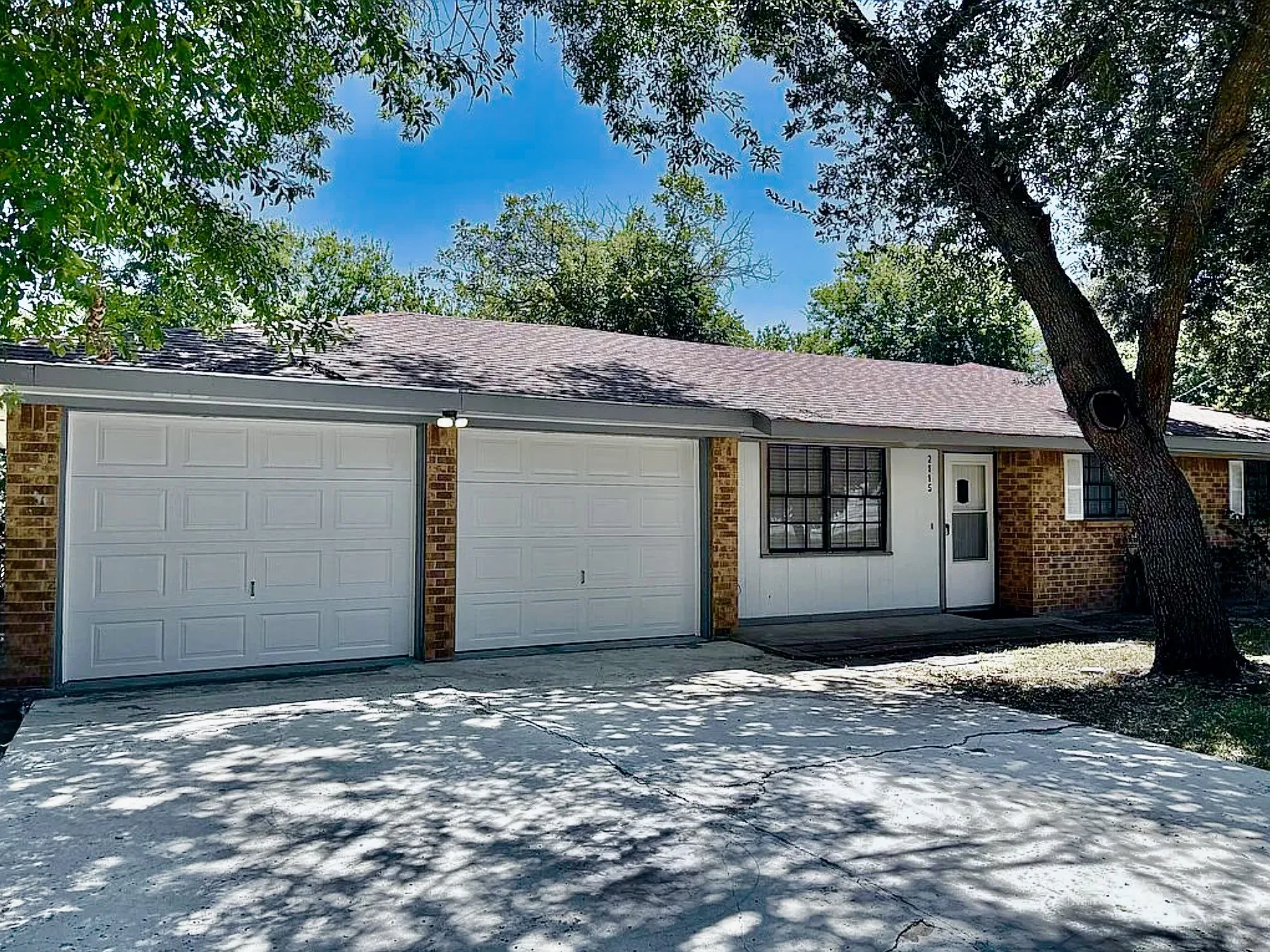 Brick exterior with a dual garage, a gabled roof, and a concrete driveway
