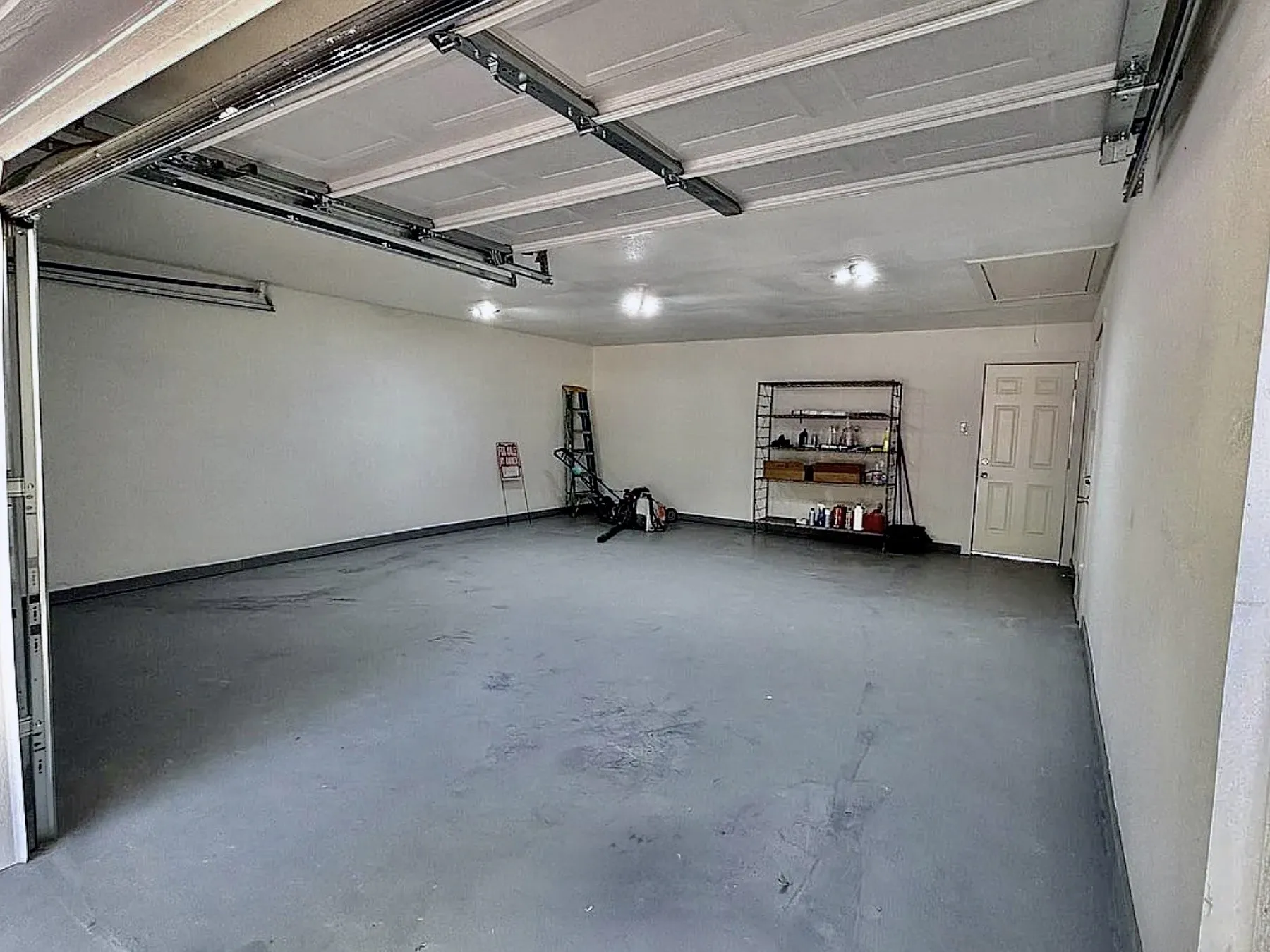 Attached garage with an overhead door, finished walls, and a dedicated entry door