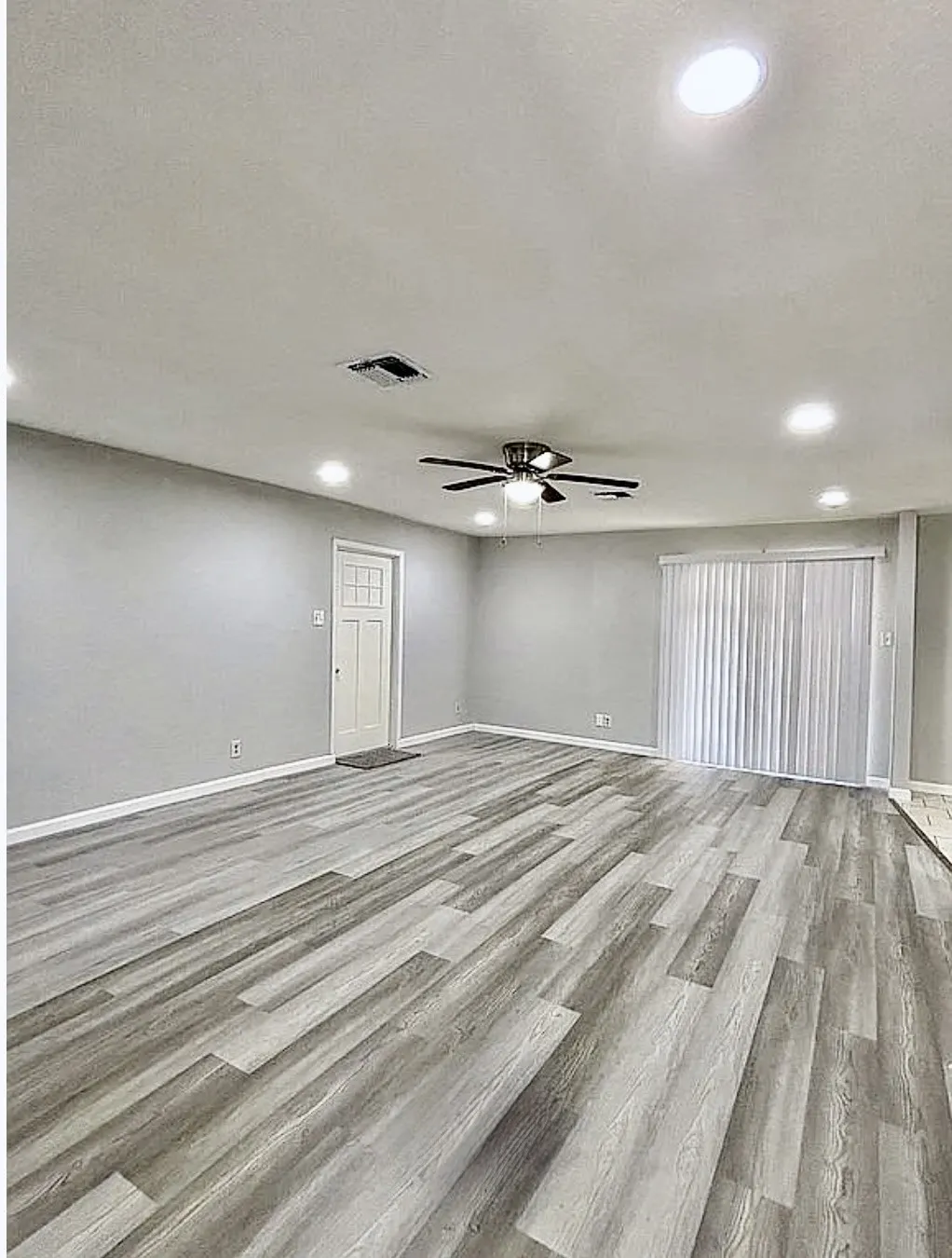 Spacious room featuring wood-finish flooring, recessed lighting, a ceiling fan, and vertical blinds