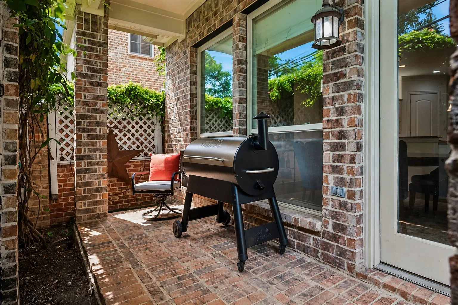 Brick patio with an outdoor wall lantern, brick walls, and white lattice detailing