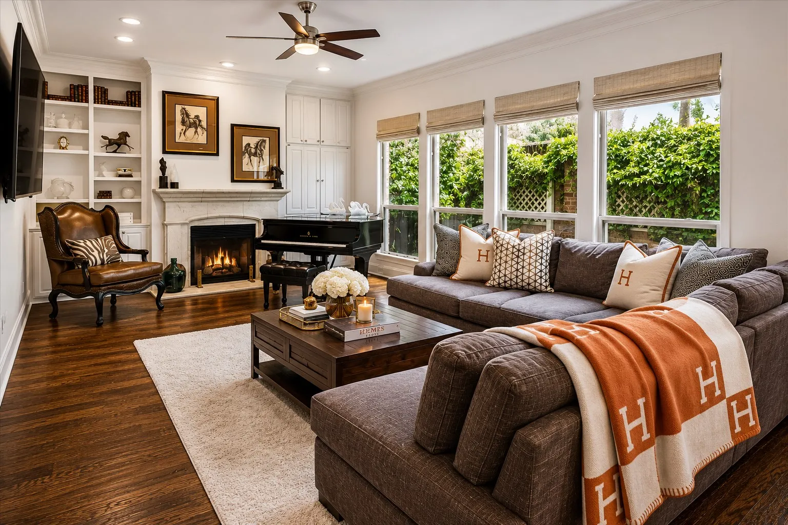 Hardwood flooring, built-in shelving, fireplace with stone surround, recessed lighting, and large windows with privacy coverings