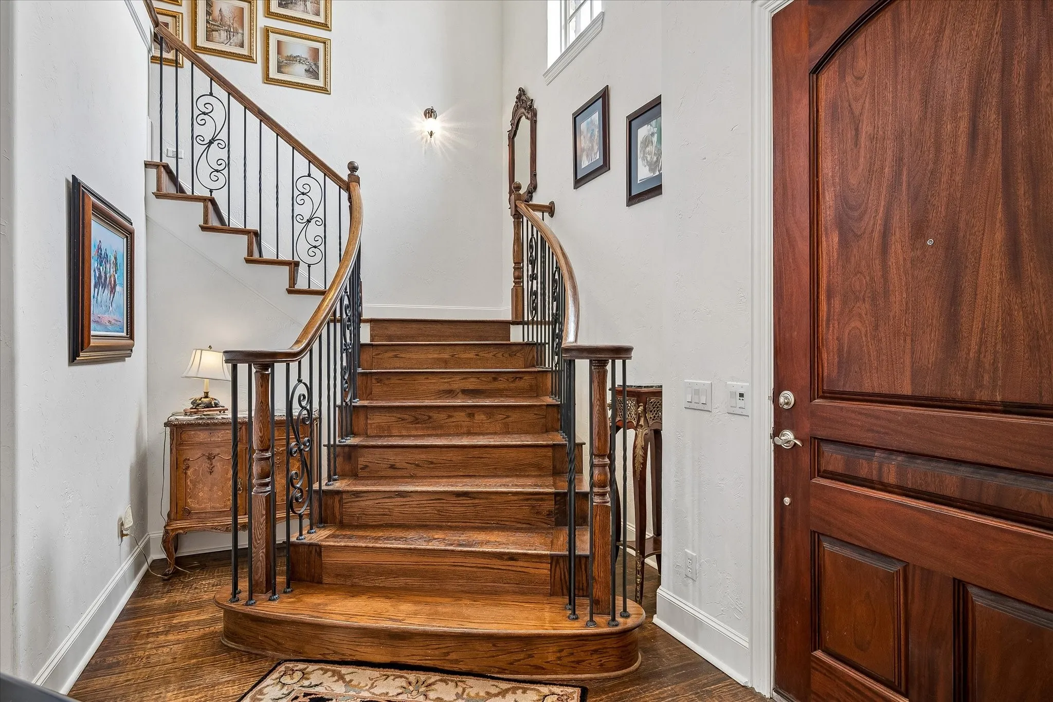 Grand curved staircase with wood treads and wrought iron balusters