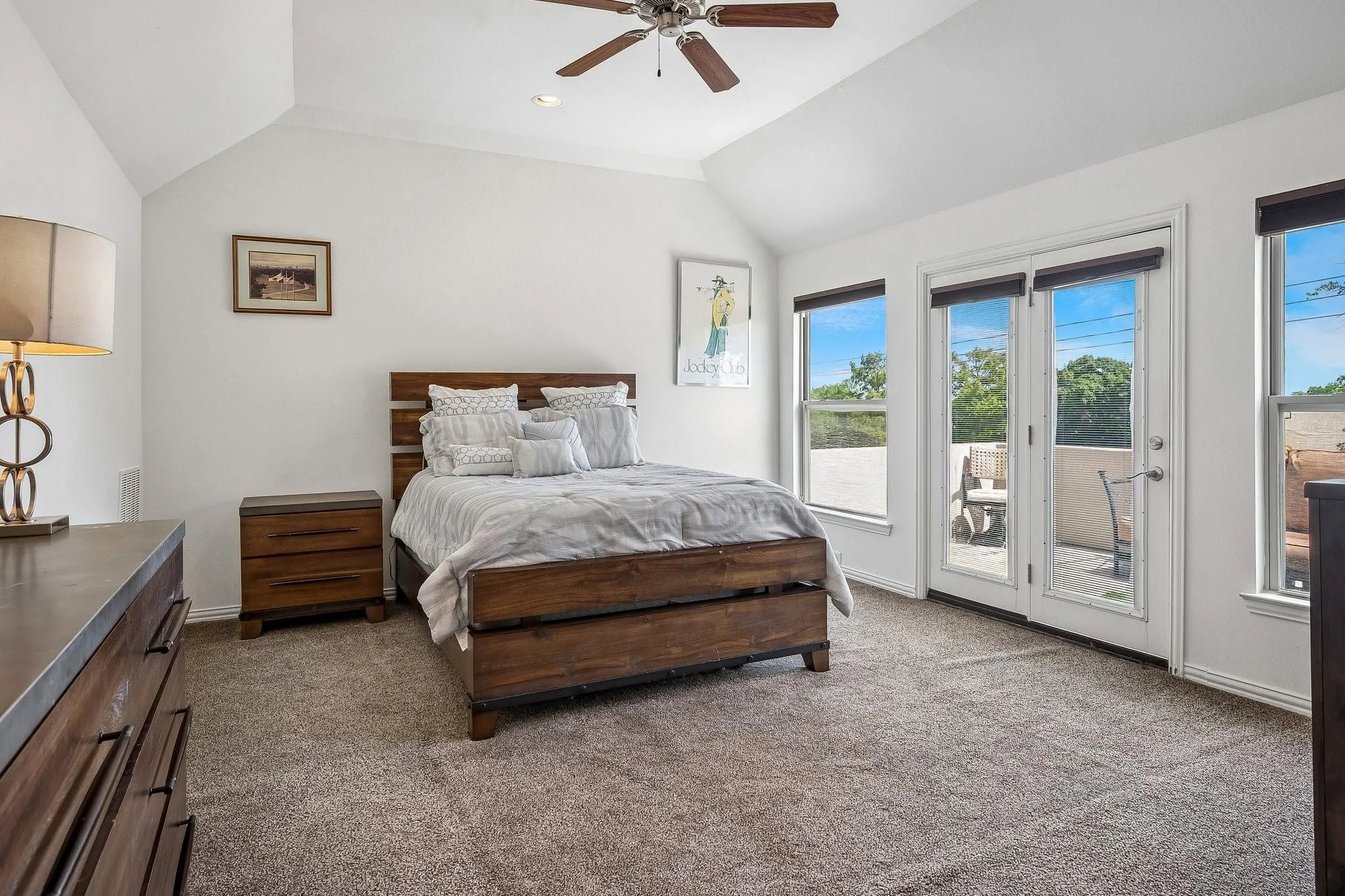 Vaulted ceiling with a ceiling fan, French doors, multiple windows, and carpeted flooring