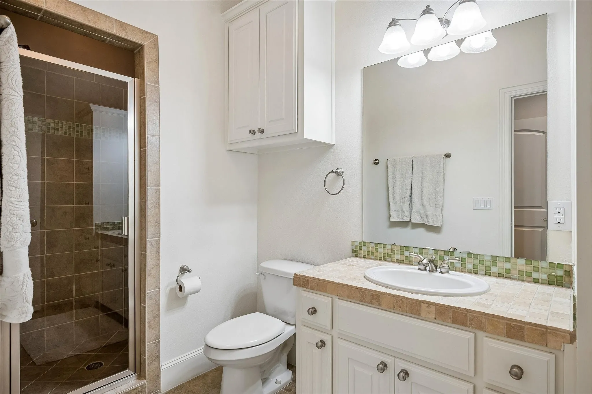 Walk-in shower with glass enclosure and tiled surround