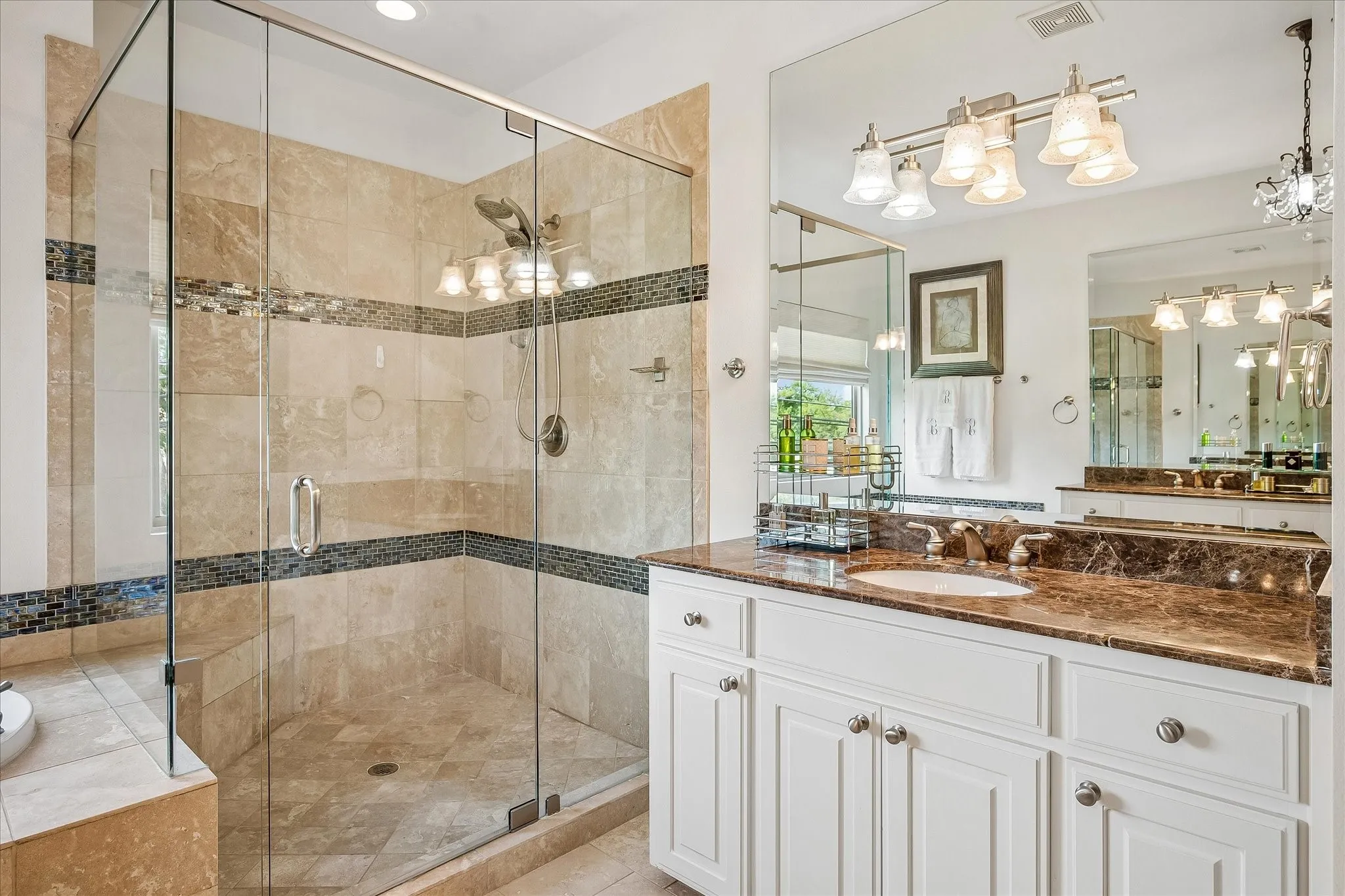 Glass-enclosed shower with stone tile surround and mosaic accent