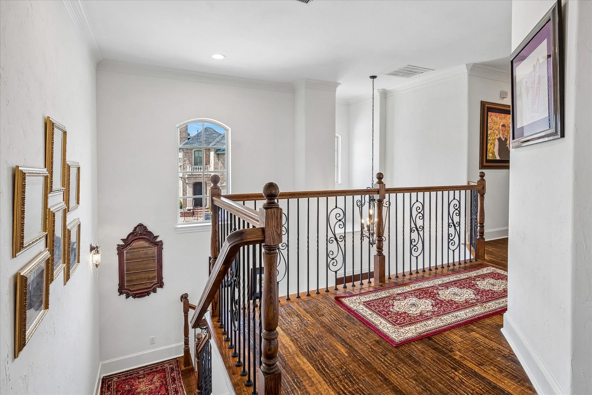 Hardwood flooring, wrought iron and wood balustrade, arched window, high ceilings, and wall sconces