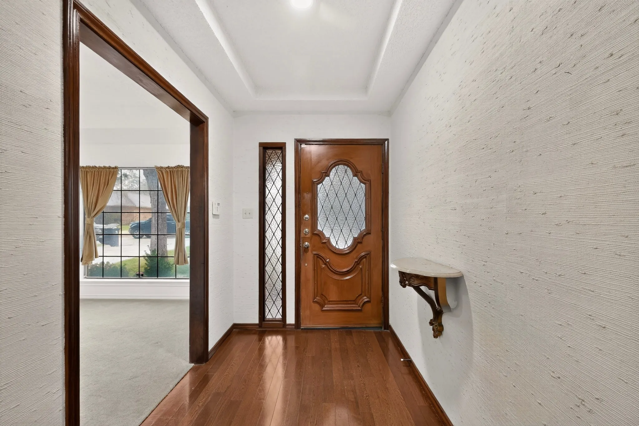 Wood-finish flooring leading to a decorative wood entry door with leaded glass
