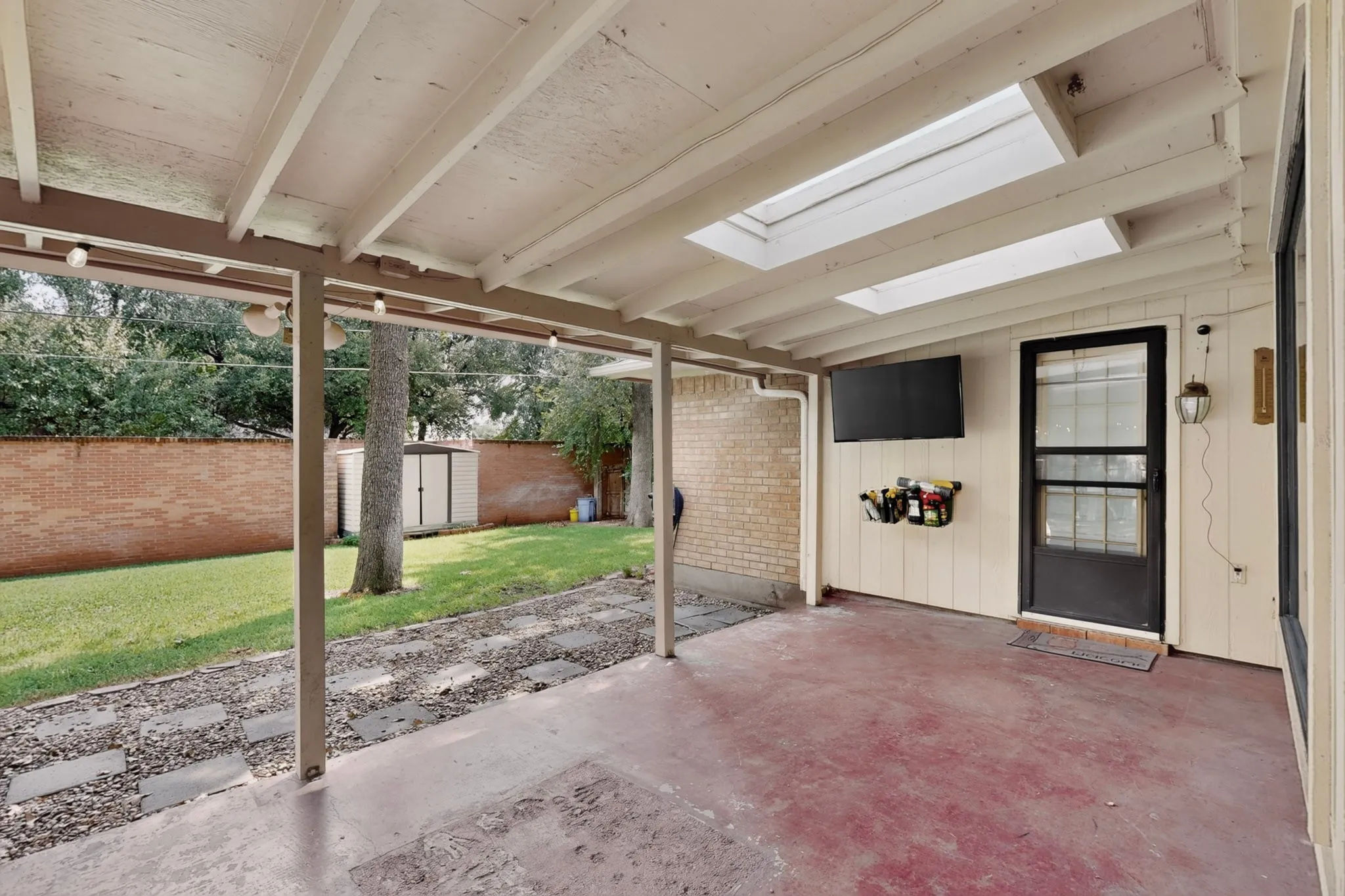 Covered patio with integrated skylights, concrete flooring, and an exterior door with a screen