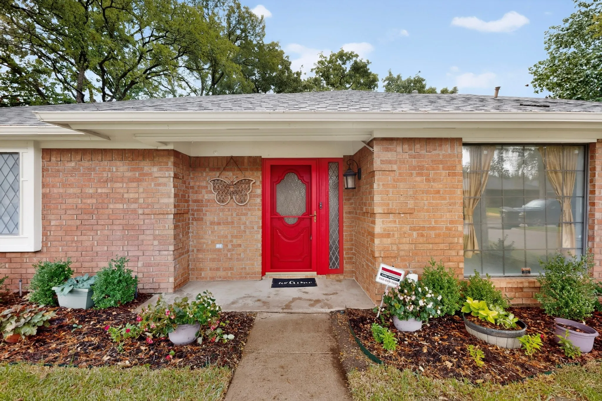 Brick exterior with a vibrant red entry door, white trim, and a gabled roof