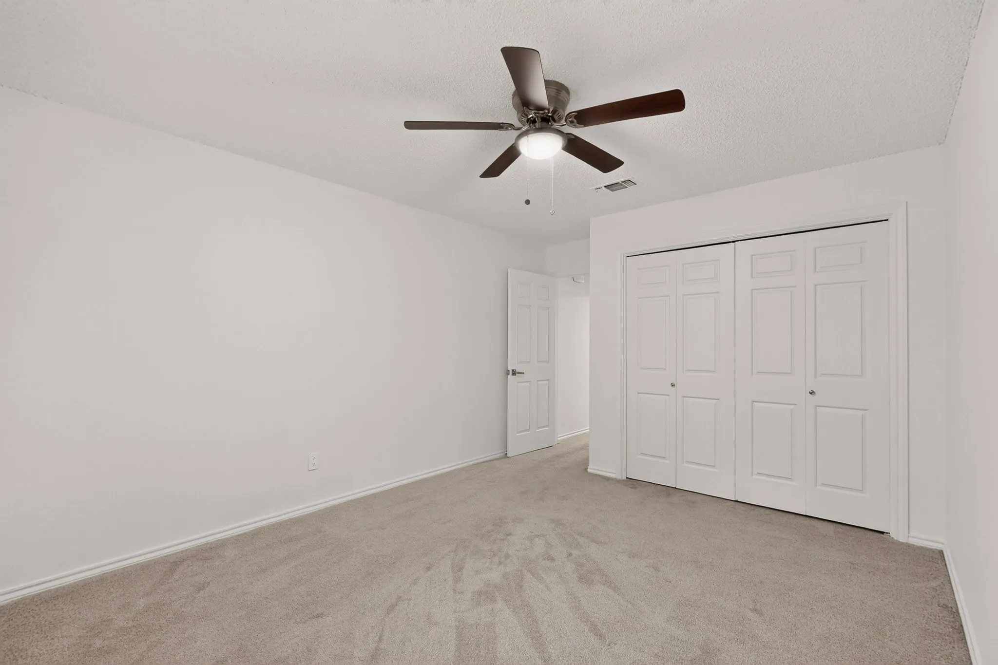 Spacious room with carpet flooring, a ceiling fan with integrated lighting, and bi-fold closet doors