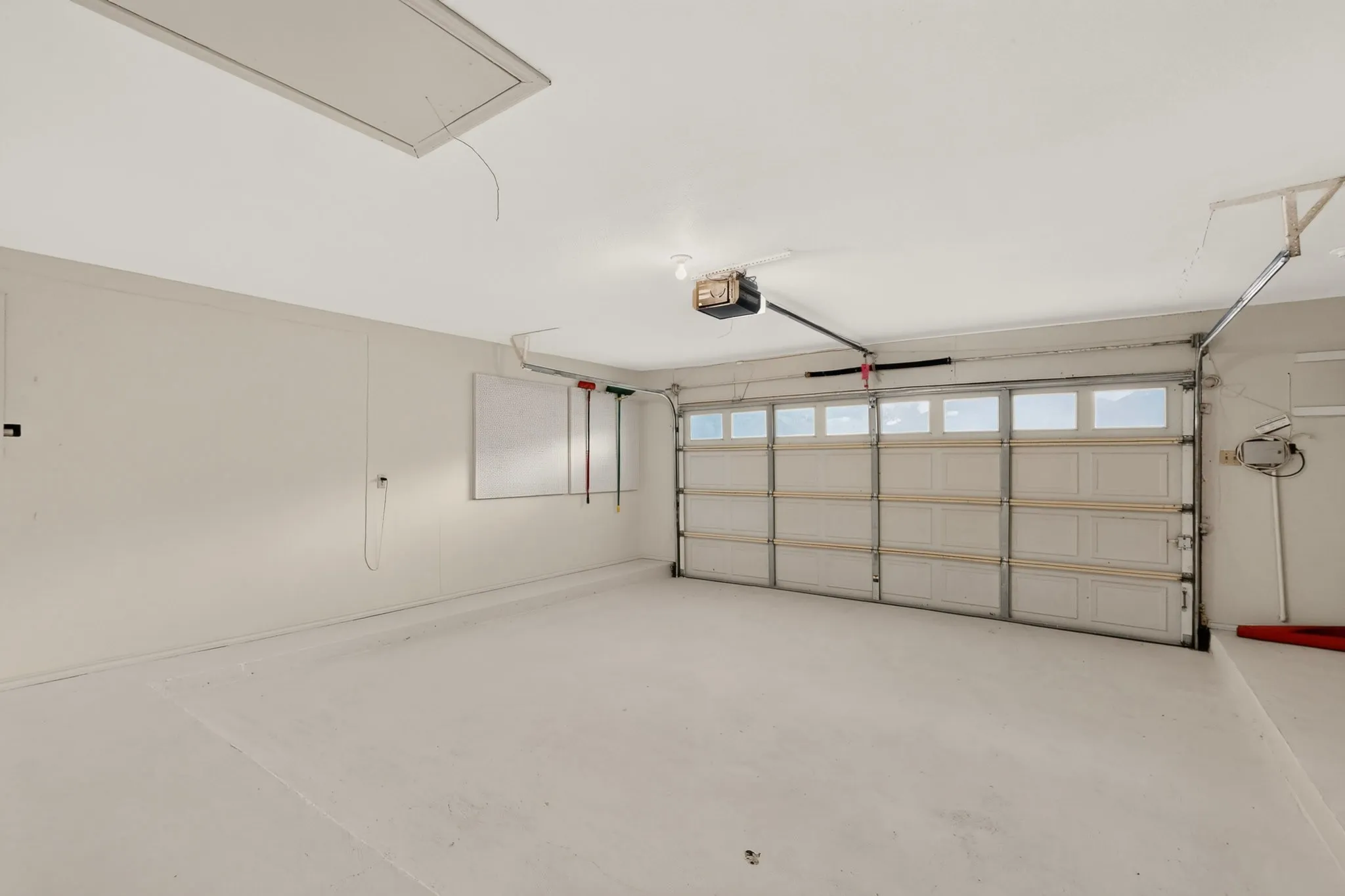 Attached garage with a panel garage door featuring upper-level windows, an automatic garage door opener, and a ceiling-mounted light fixture