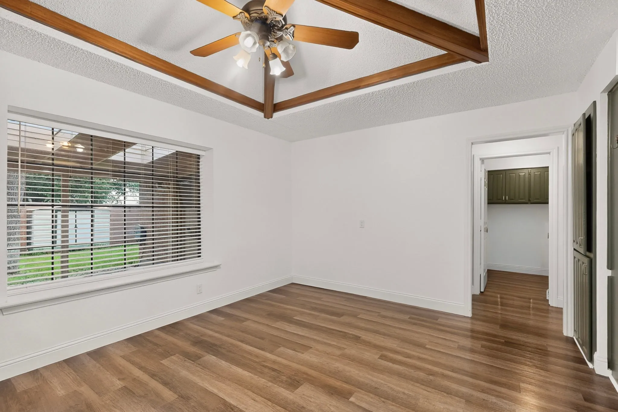 Vaulted ceiling with exposed wood beams, wood-finish flooring, recessed window, and built-in storage cabinetry