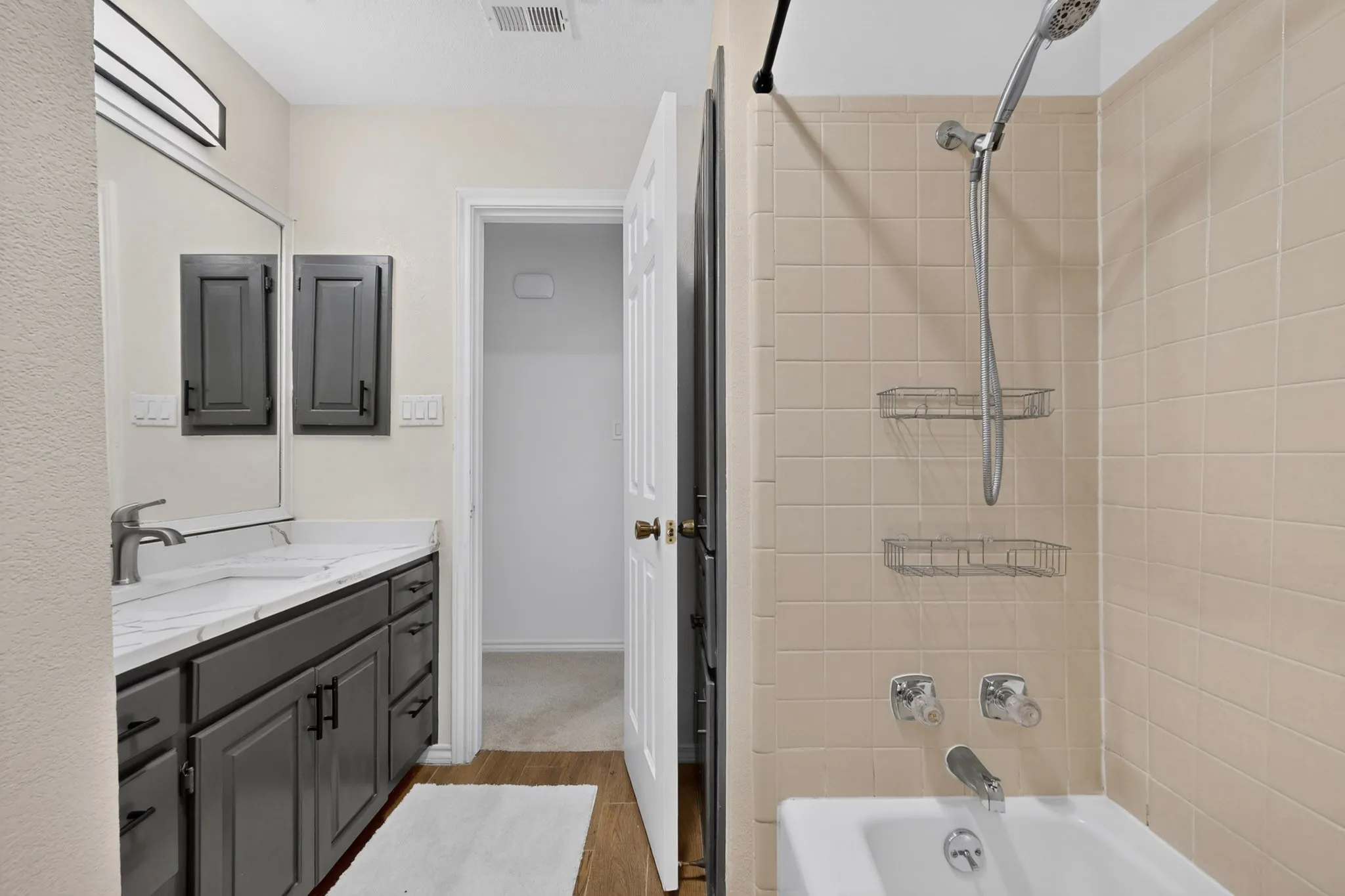 Bathroom featuring a vanity with dark cabinetry, integrated sink, and a light-colored countertop
