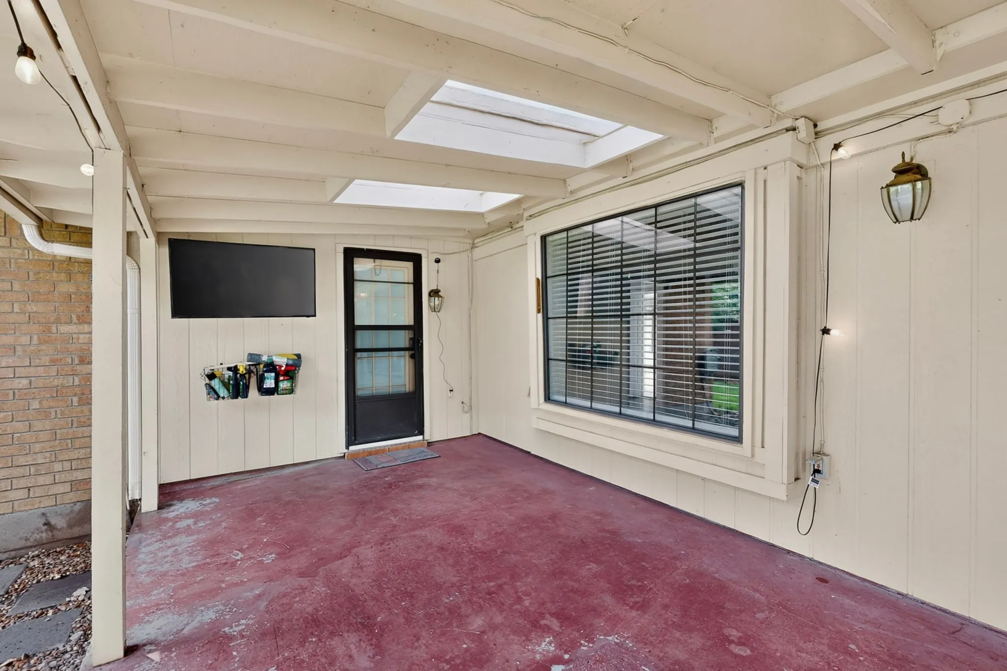 Covered patio with a painted concrete surface, skylights, and a bay window with horizontal blinds