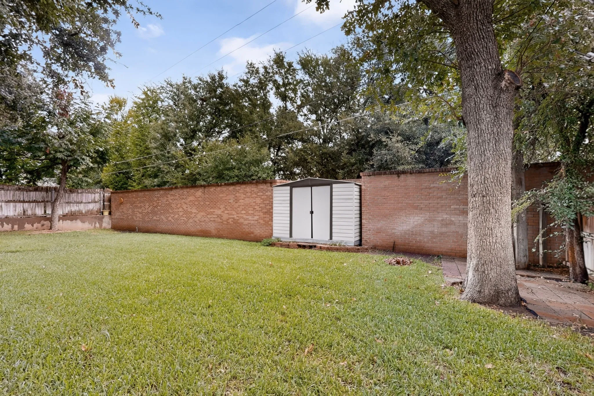 Expansive lawn area with a brick privacy wall