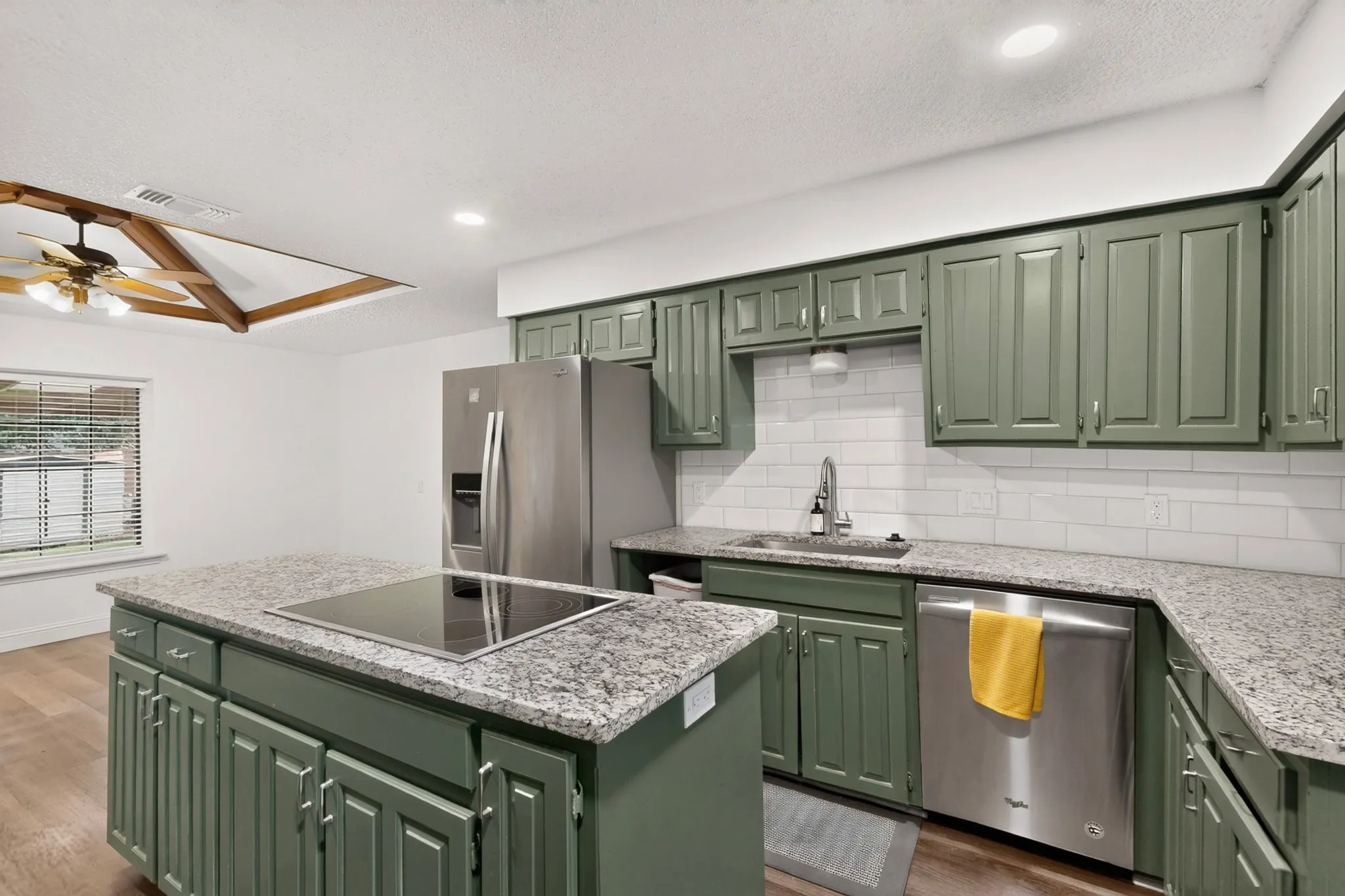 Kitchen featuring green shaker-style cabinetry, granite countertops, subway tile backsplash, and stainless steel appliances