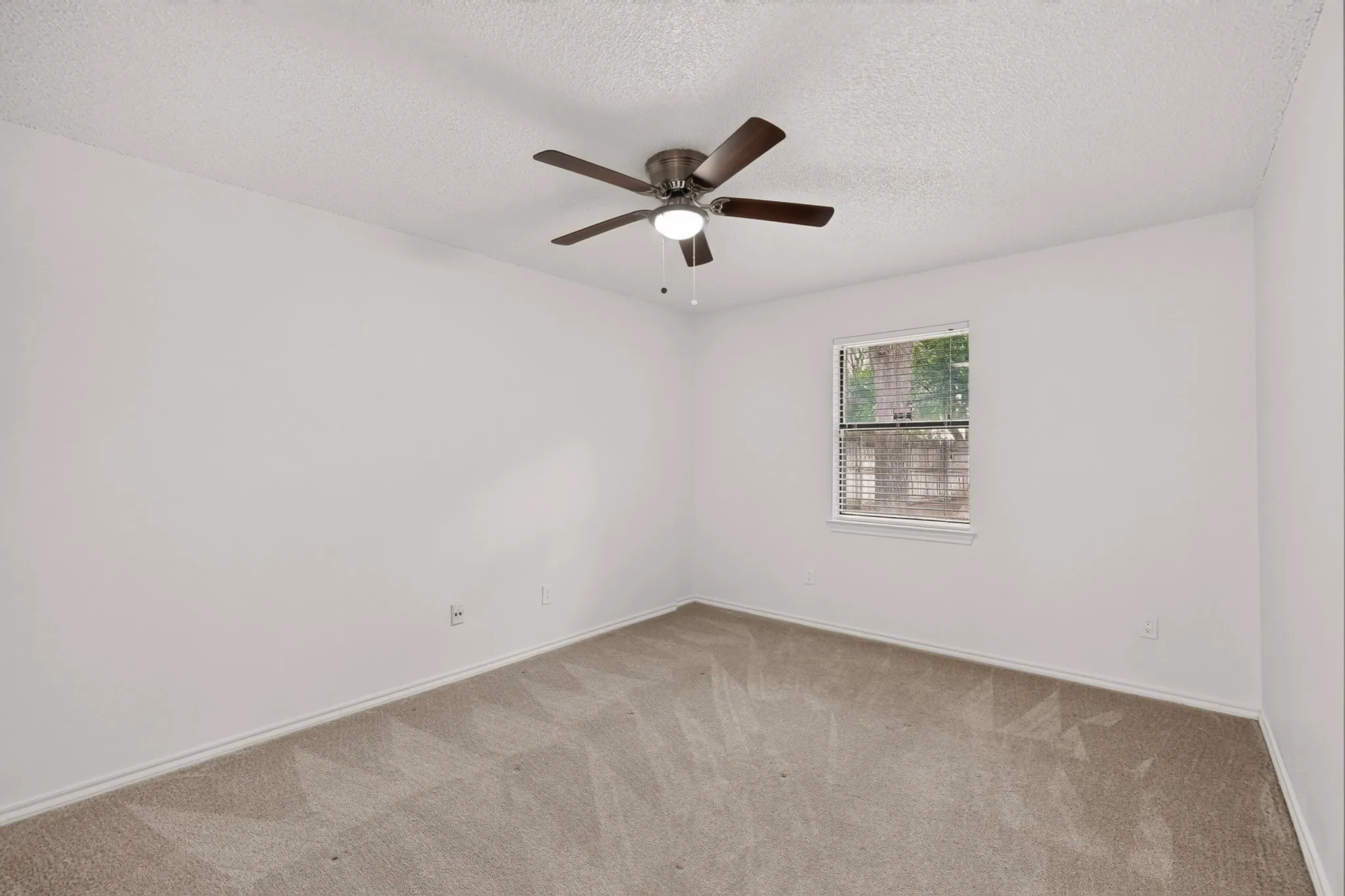 Neutral-toned carpeting, white walls, and a window with blinds
