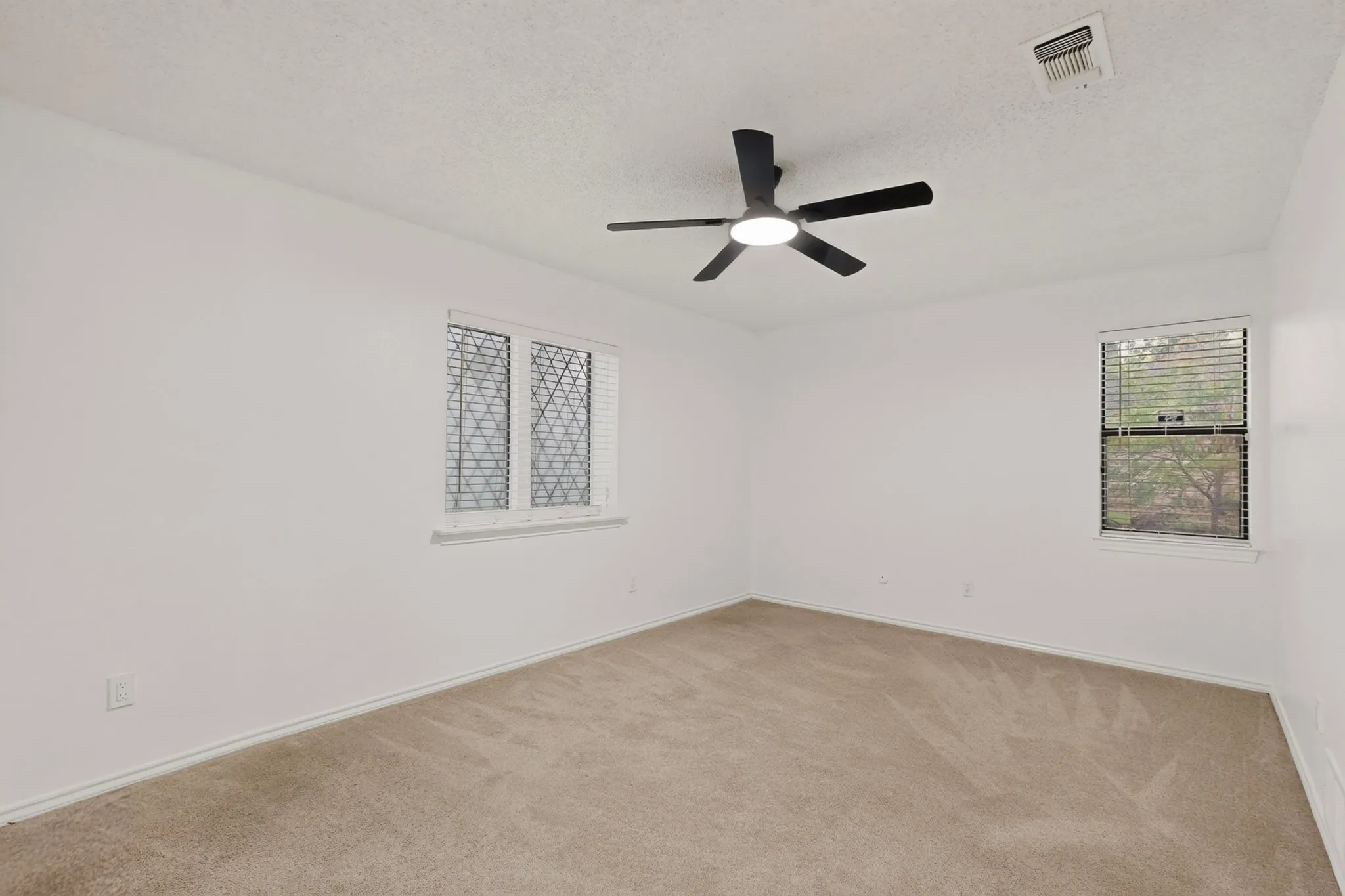 Neutral-toned carpeting, white painted walls, and a contemporary ceiling fan with integrated lighting