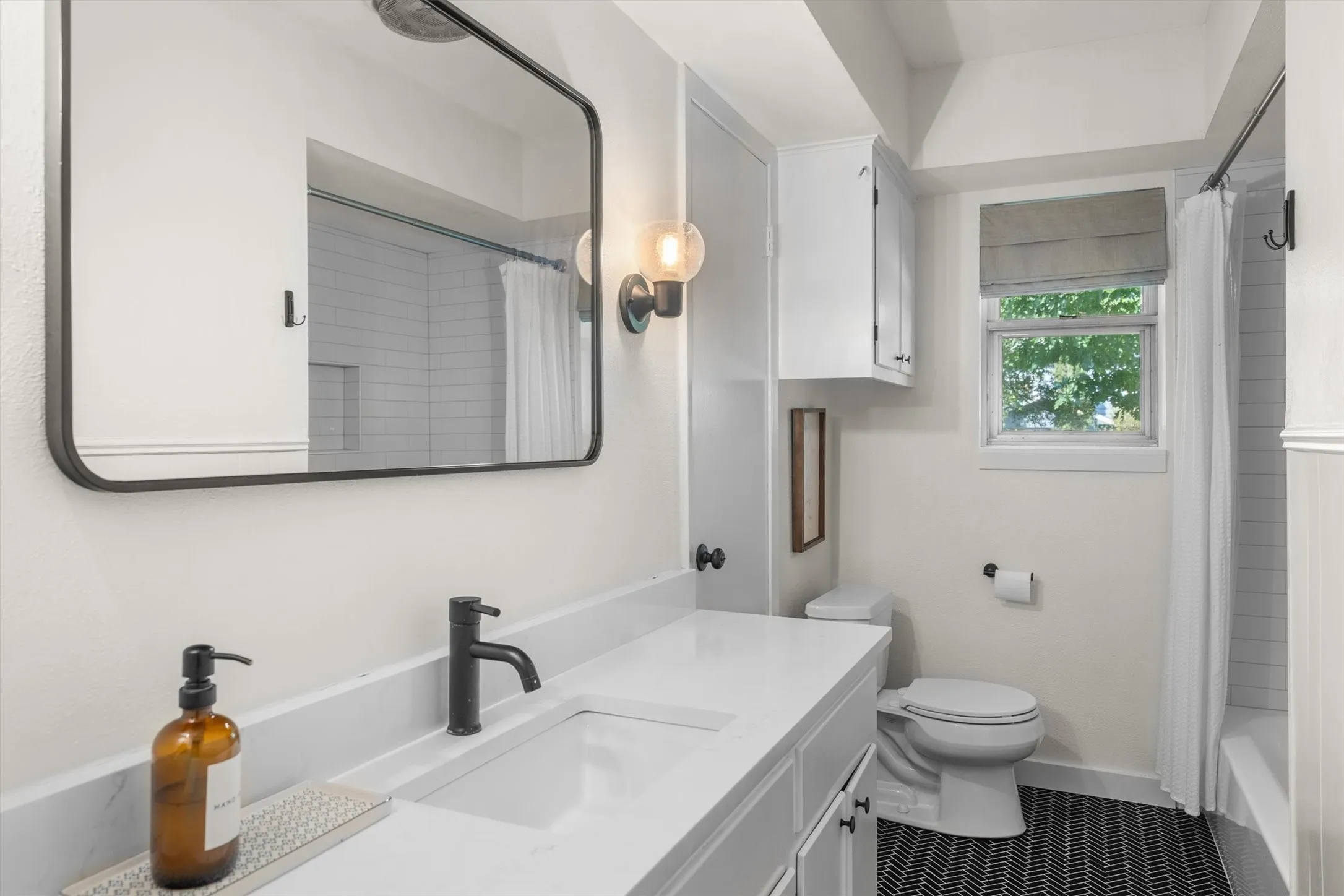 Updated guest bath has an extra large vanity and updated shower/tub combo.