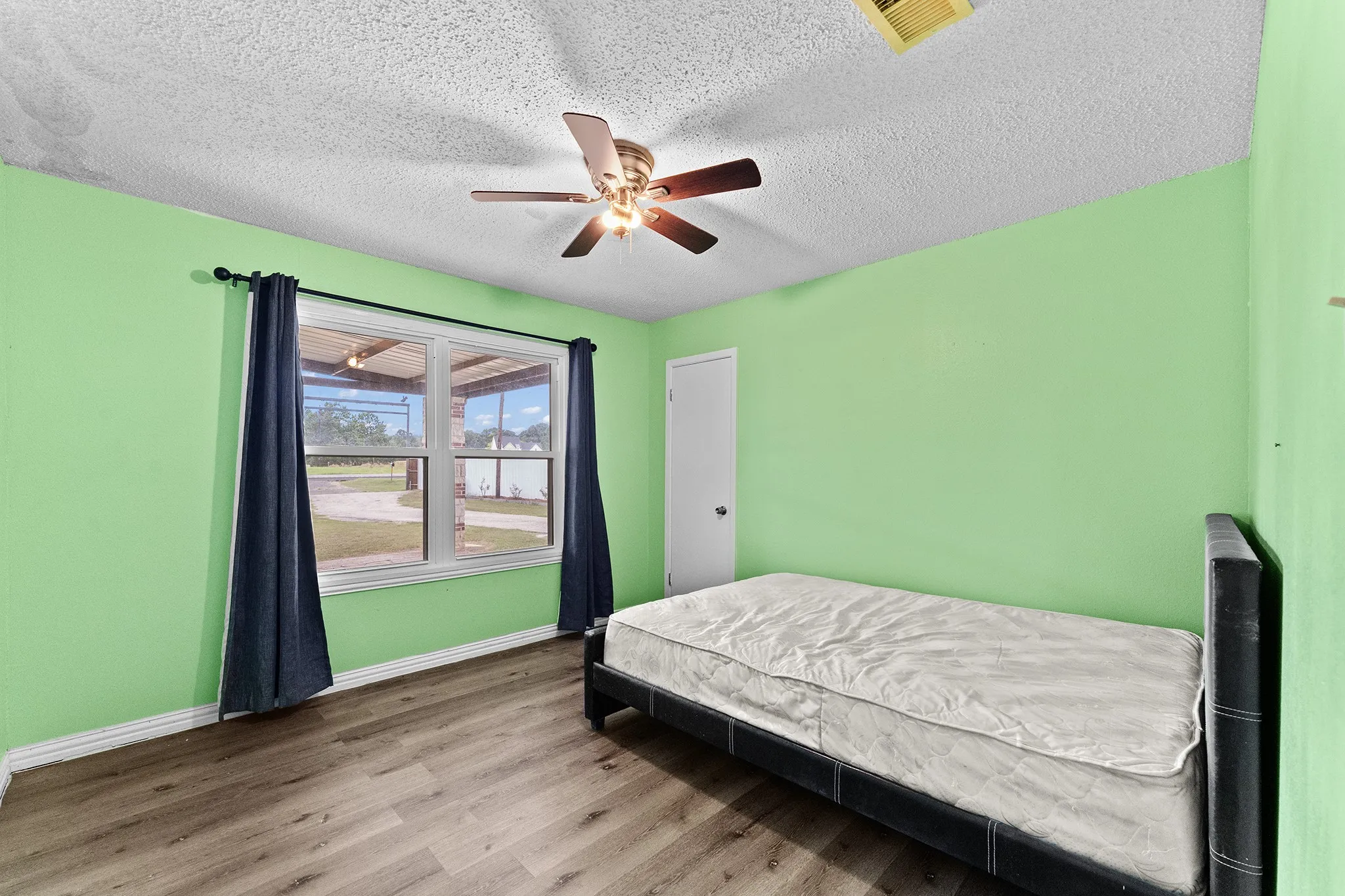 Wood-finish flooring with a ceiling fan light fixture and a window with white trim
