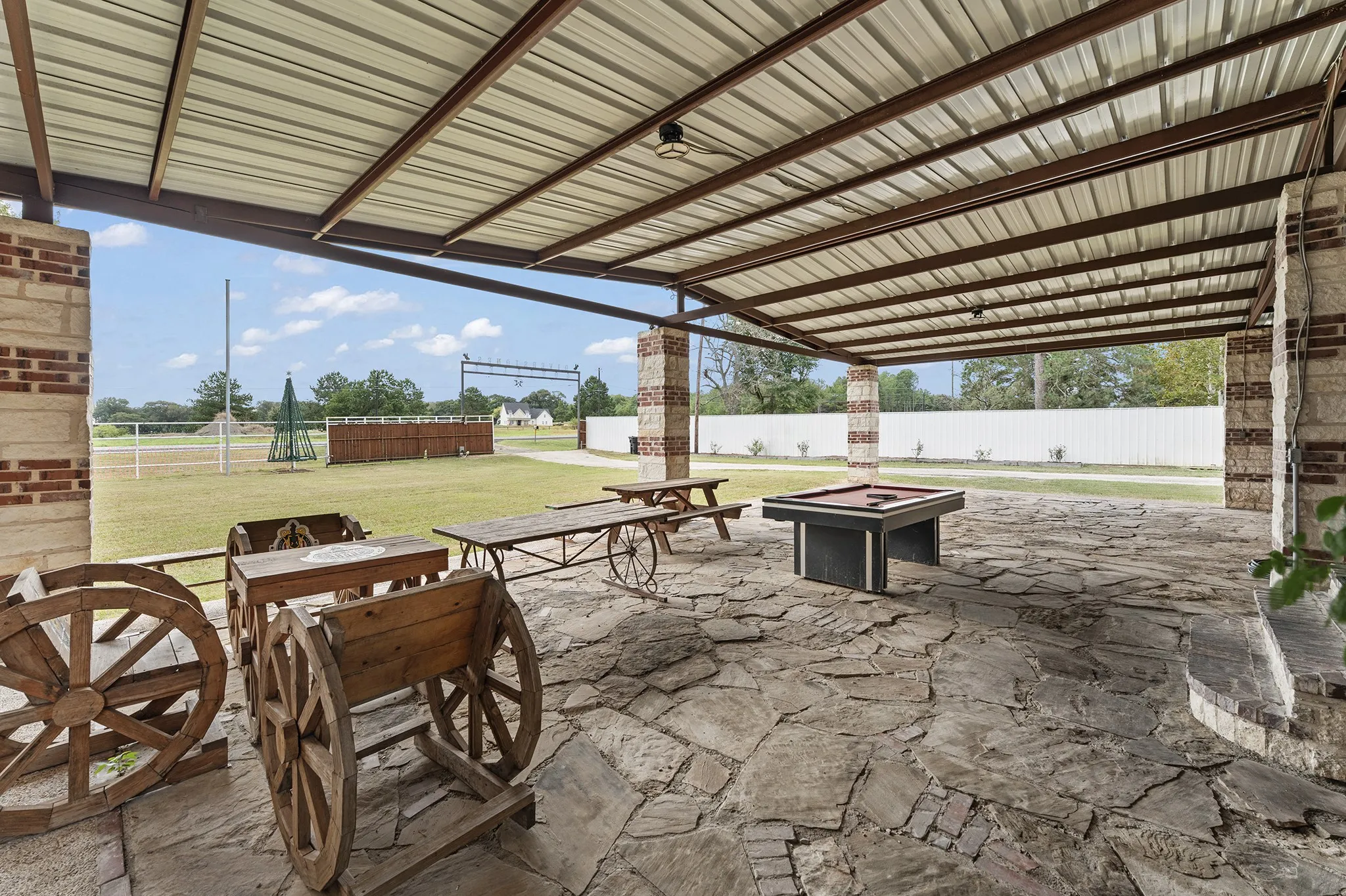 Expansive covered patio featuring a metal roof, brick and stone columns, and flagstone flooring
