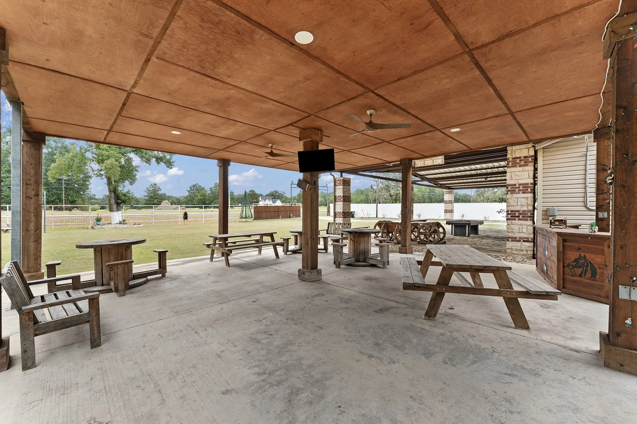 Expansive covered patio featuring a concrete floor, wood-paneled ceiling, recessed lighting, and ceiling fans