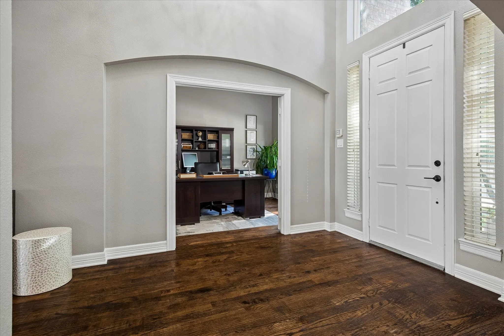Hardwood flooring, arched doorway, panel-style front door, side-light windows, built-in shelving