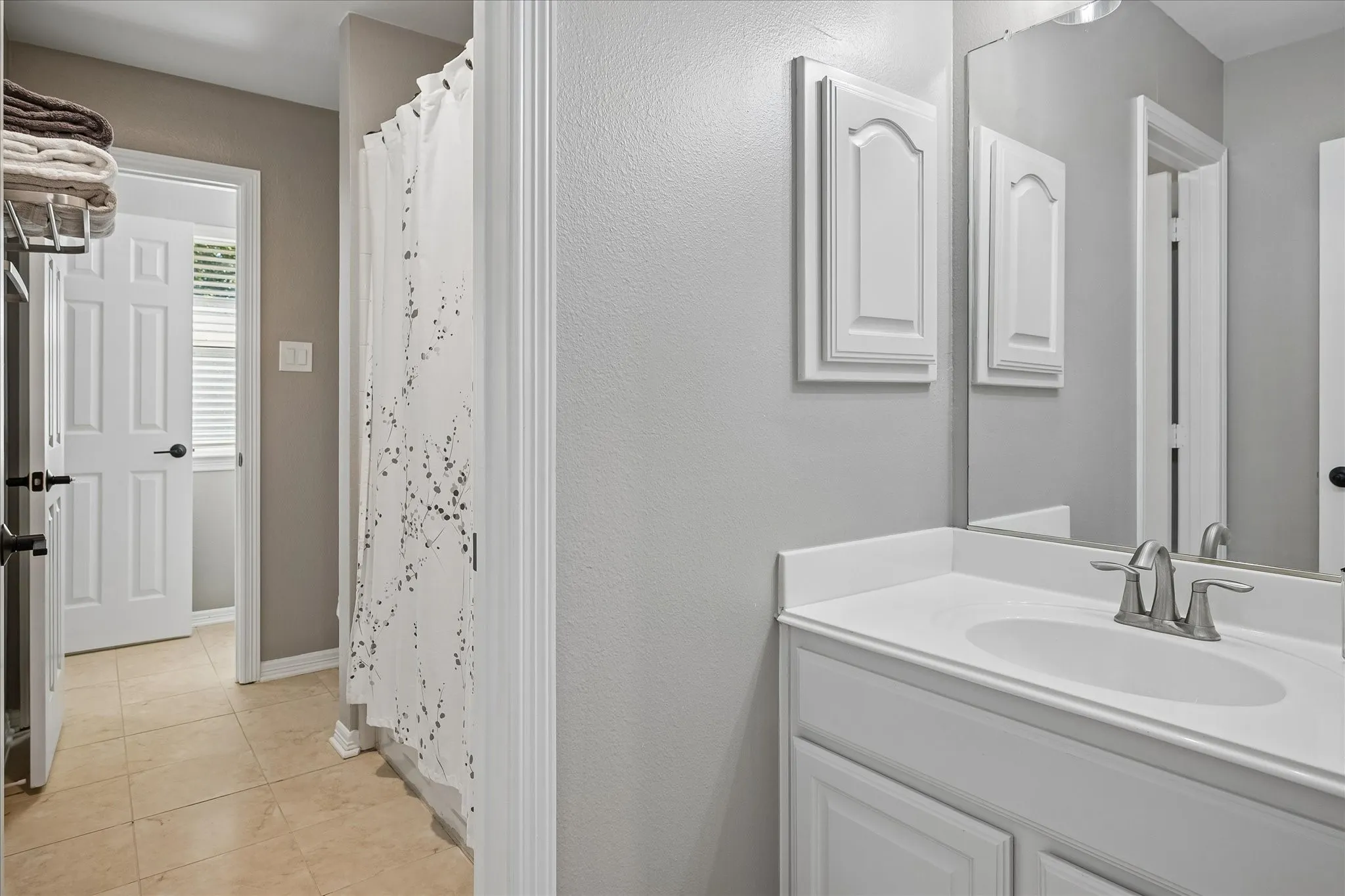 White vanity with a single basin sink, brushed nickel faucet, and a large wall-mounted mirror