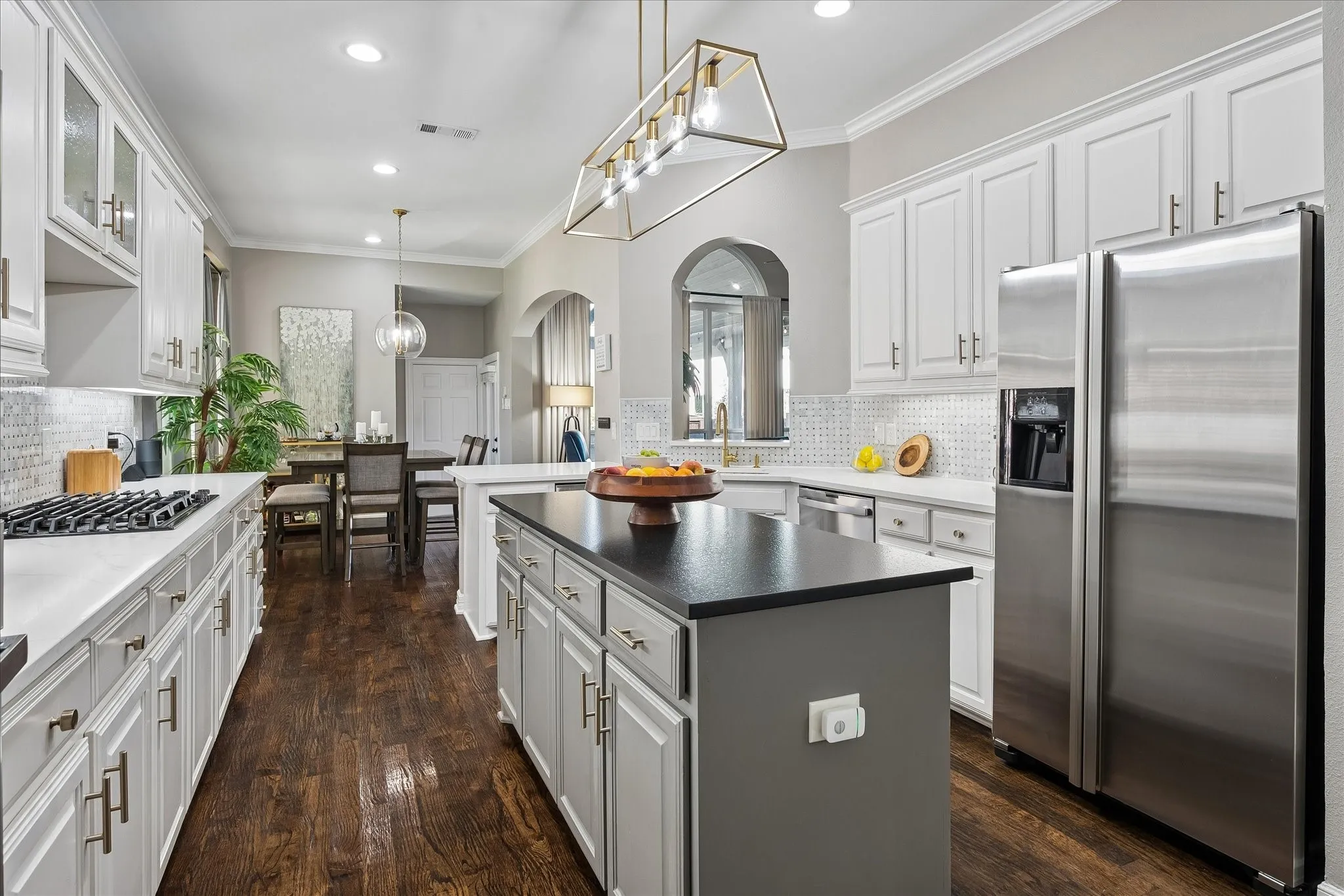 Gourmet kitchen with white cabinetry, dark wood-finish flooring, stainless steel appliances, a center island with a dark countertop, and recessed lighting