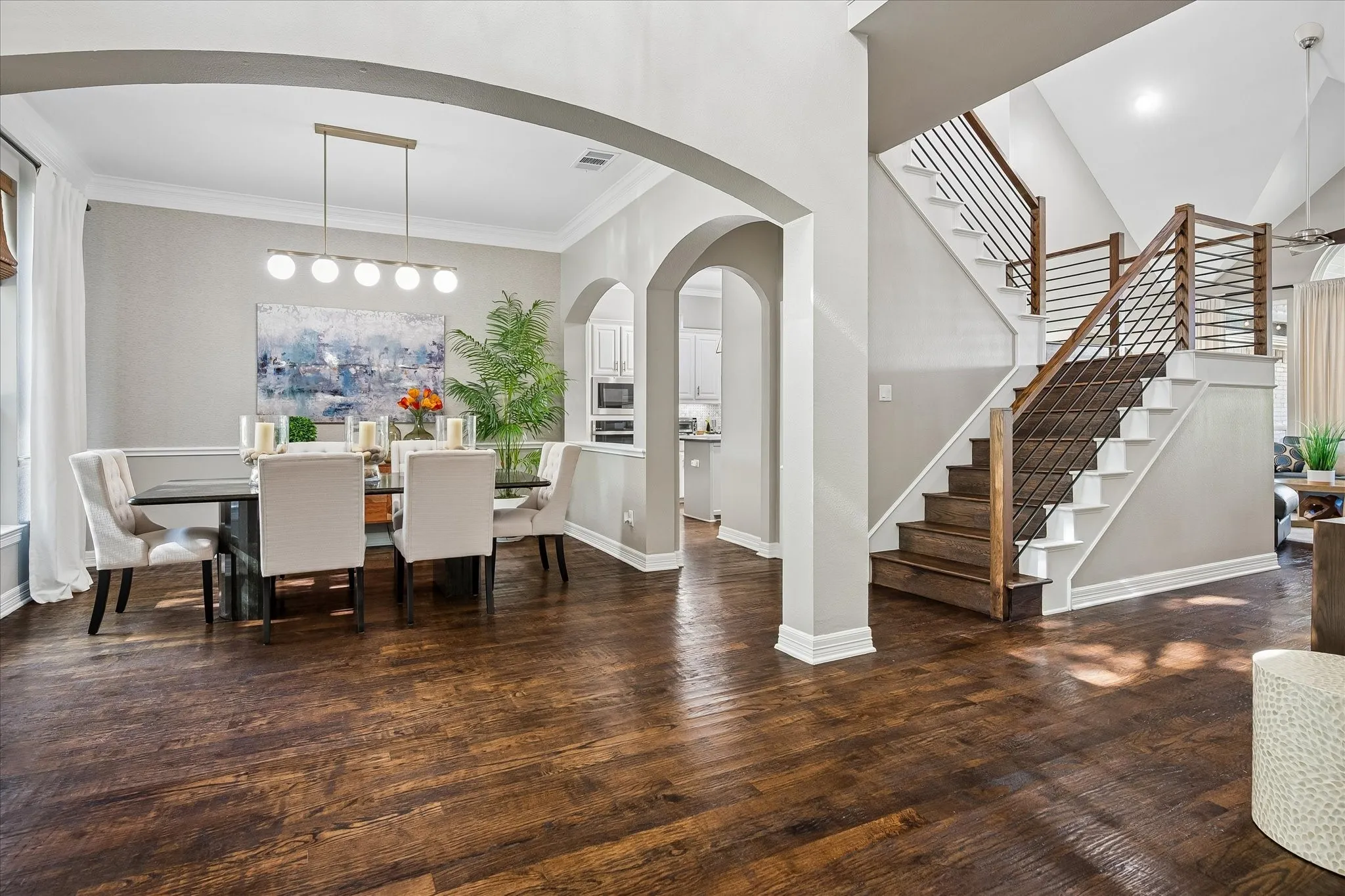 Hardwood flooring throughout, arched doorways, a contemporary staircase with wood and metal railing, recessed lighting, and crown molding