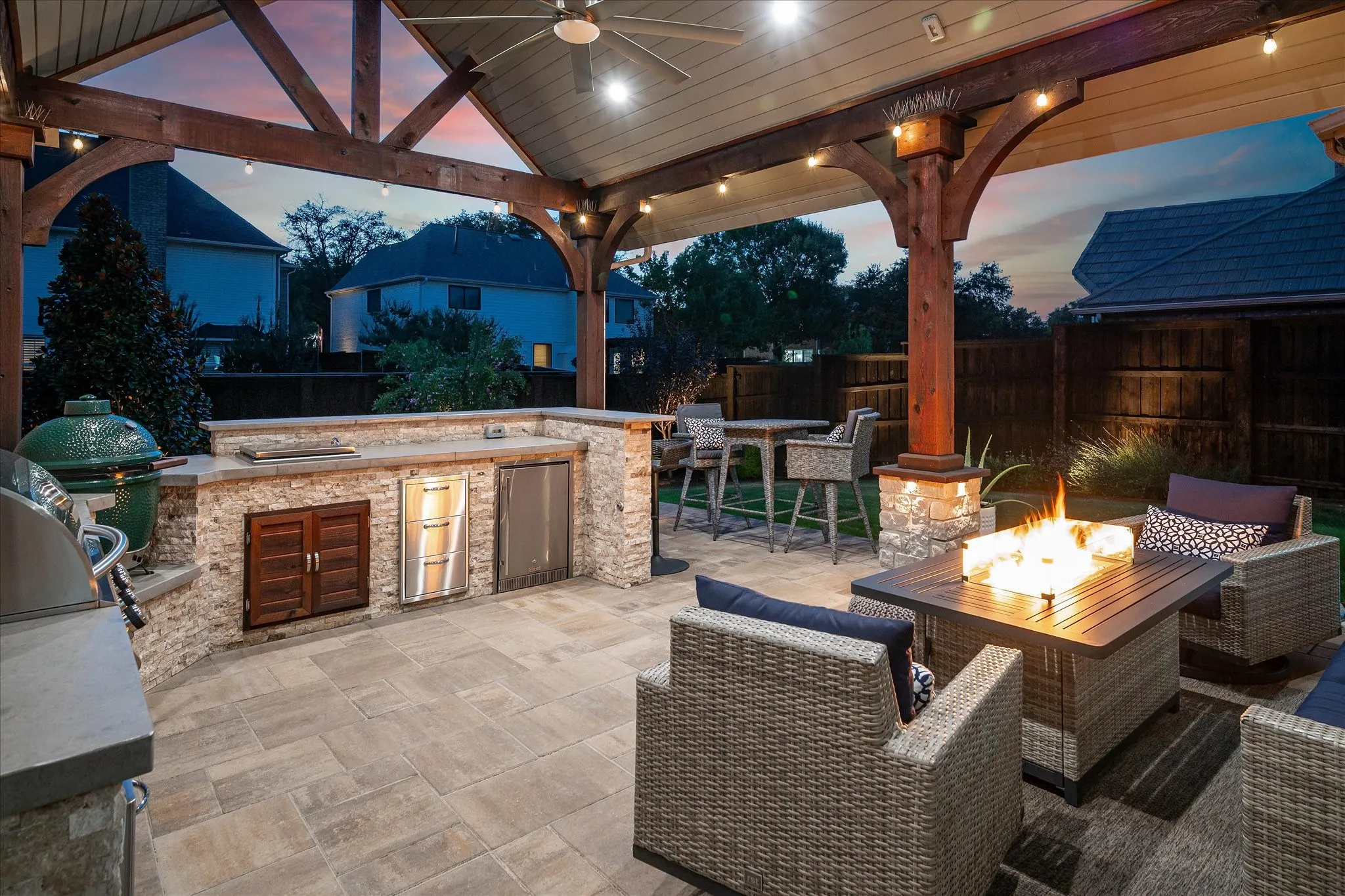 Covered outdoor patio with exposed beam ceiling, built-in outdoor kitchen, stone fire pit, and paver flooring