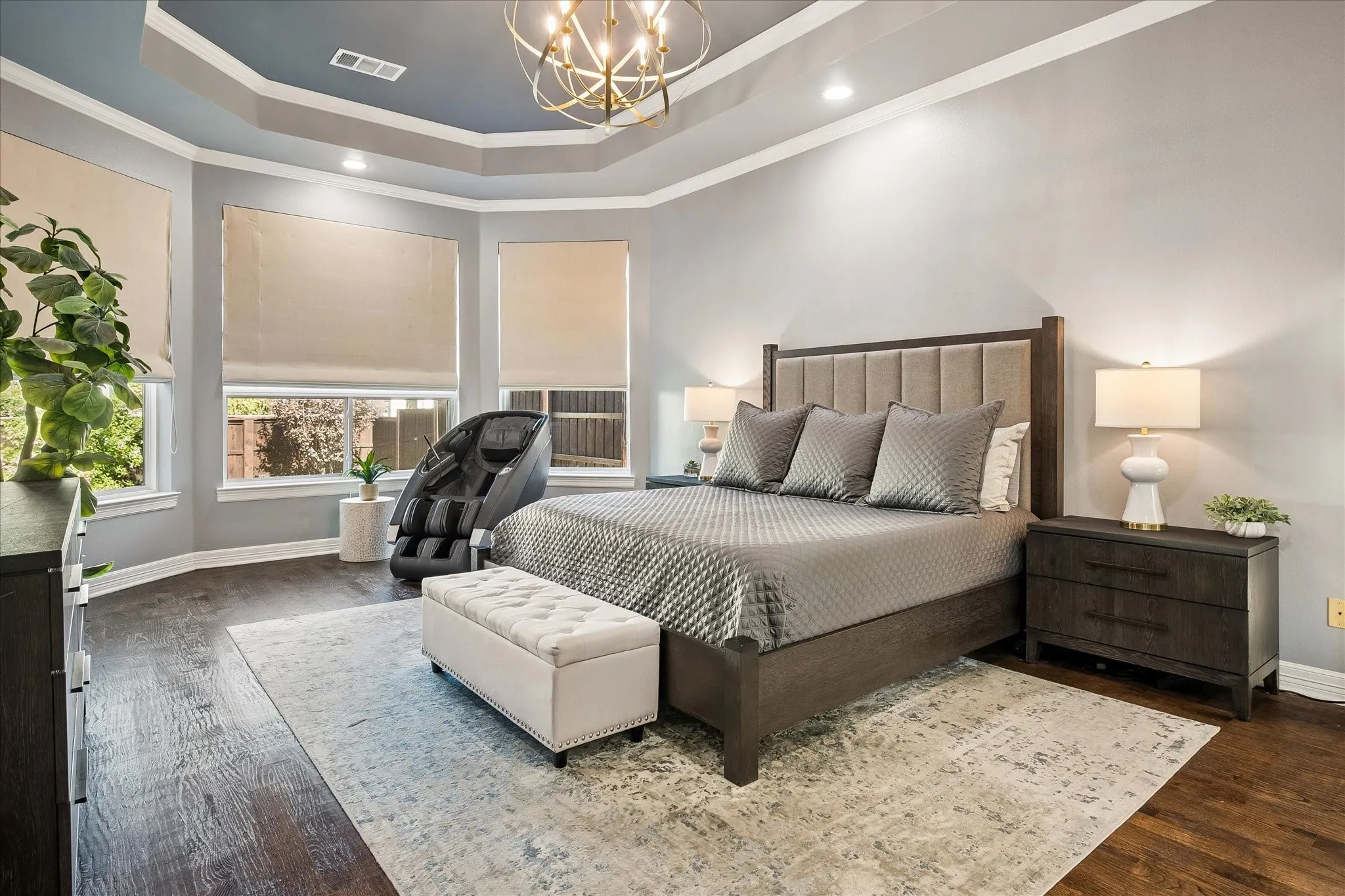 Tray ceiling with recessed lighting and a decorative chandelier, wood-finish flooring, and multiple windows with roller shades