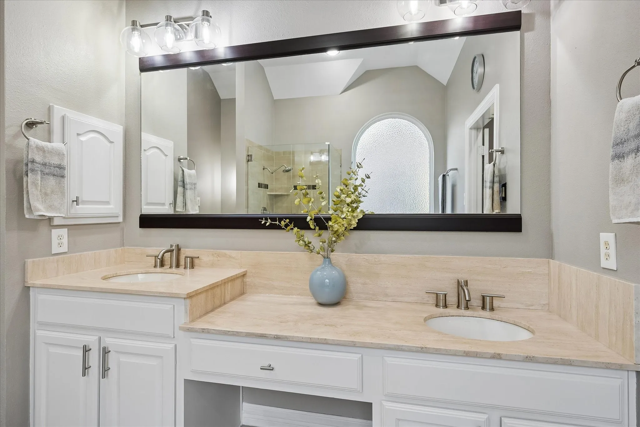 Dual vanity with light-toned countertops, white cabinetry, undermount sinks, and brushed nickel fixtures