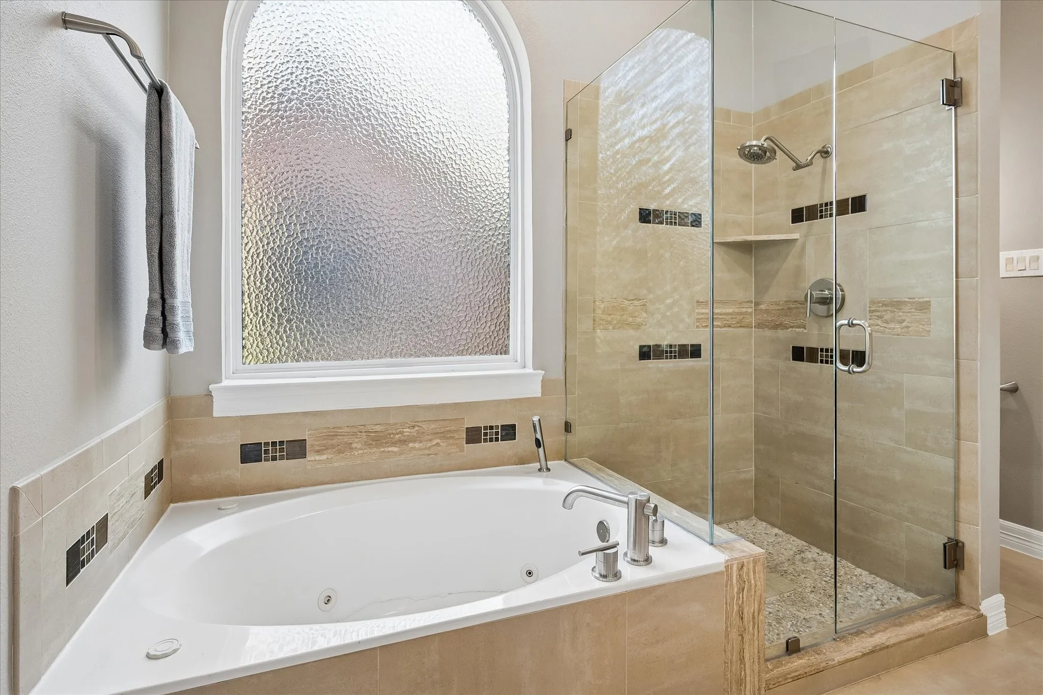 Corner soaking tub with polished chrome fixtures, framed by an arched privacy window