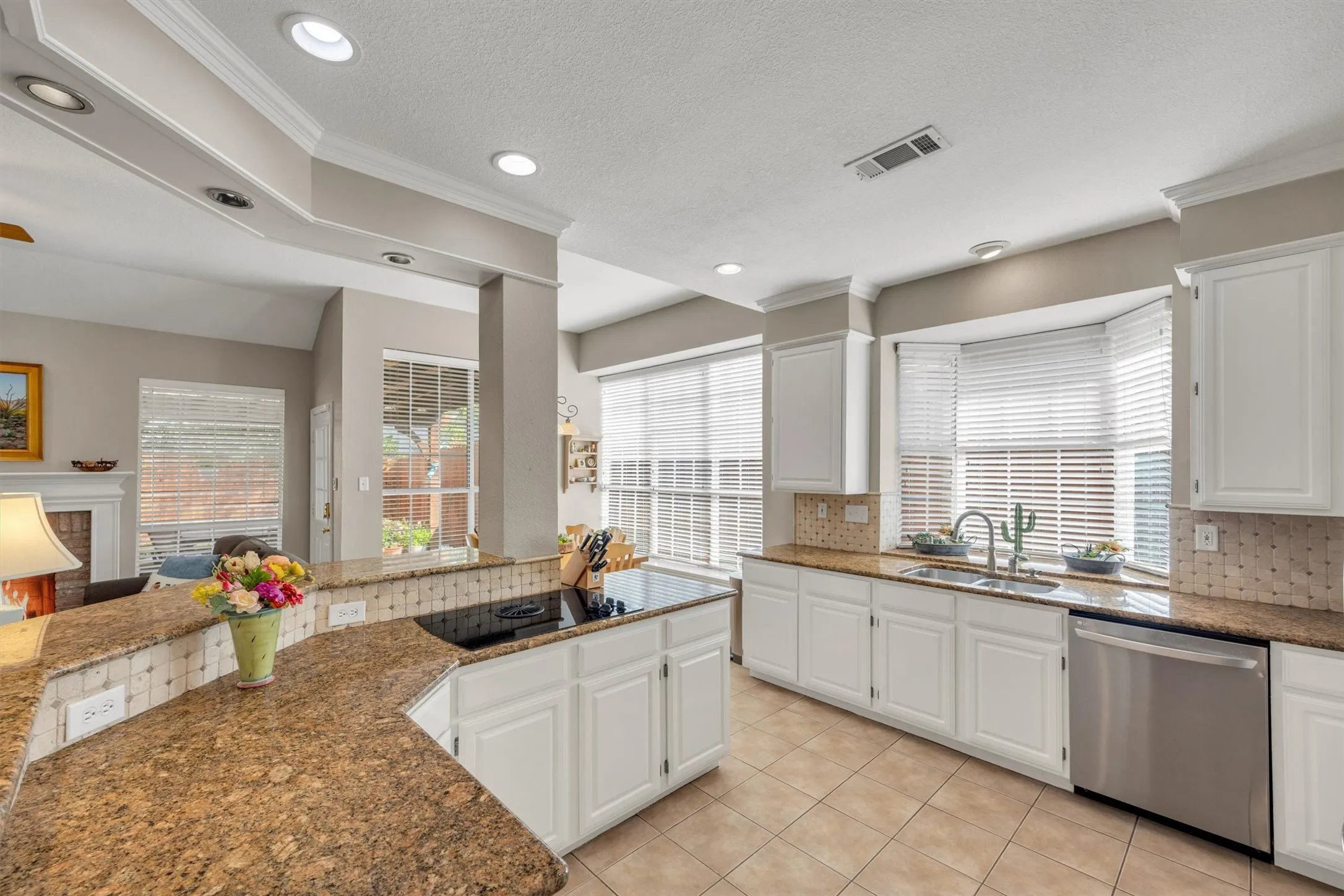 Kitchen featuring white cabinetry, granite countertops, tile flooring, and integrated stainless steel appliances.