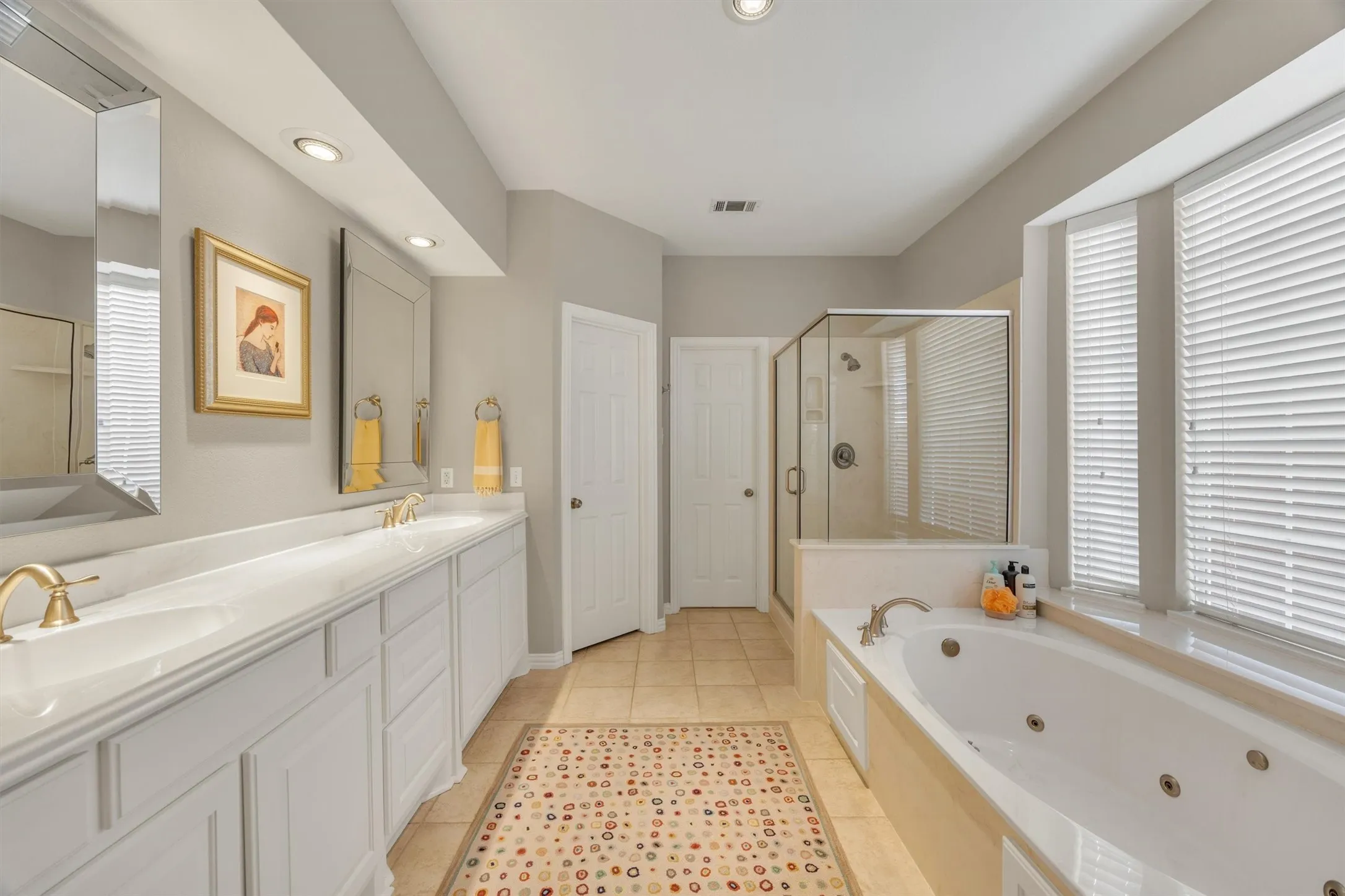 Pub-height vanity with dual undermount sinks, separate glass-enclosed shower, jetted soaking tub, and recessed lighting.