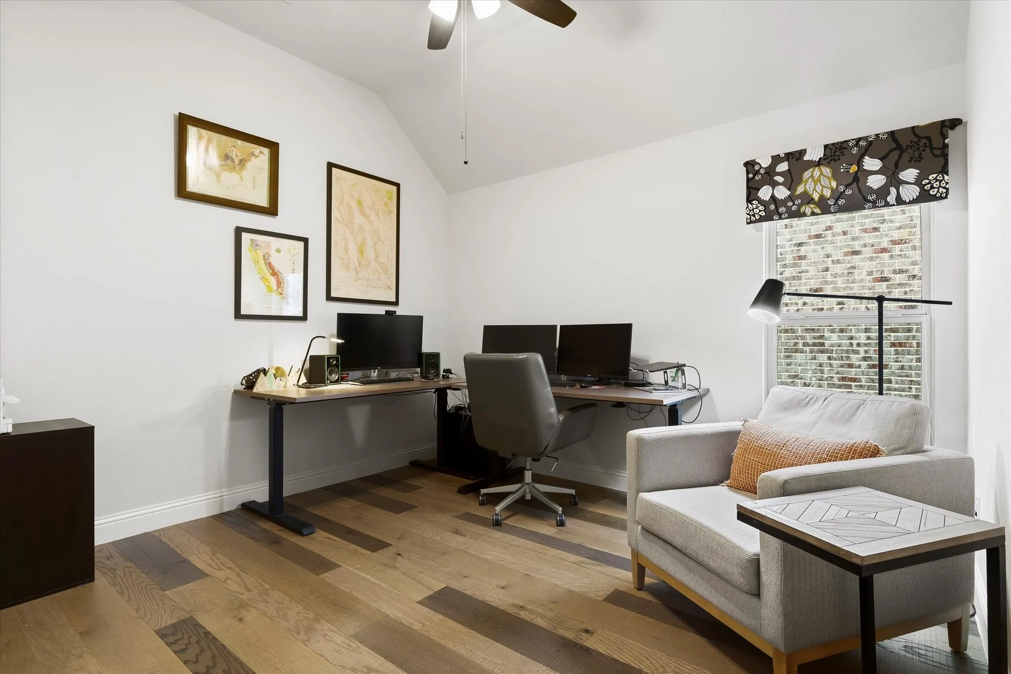 Vaulted ceiling with ceiling fan, wood-finish flooring, white walls, and a window with a patterned valance