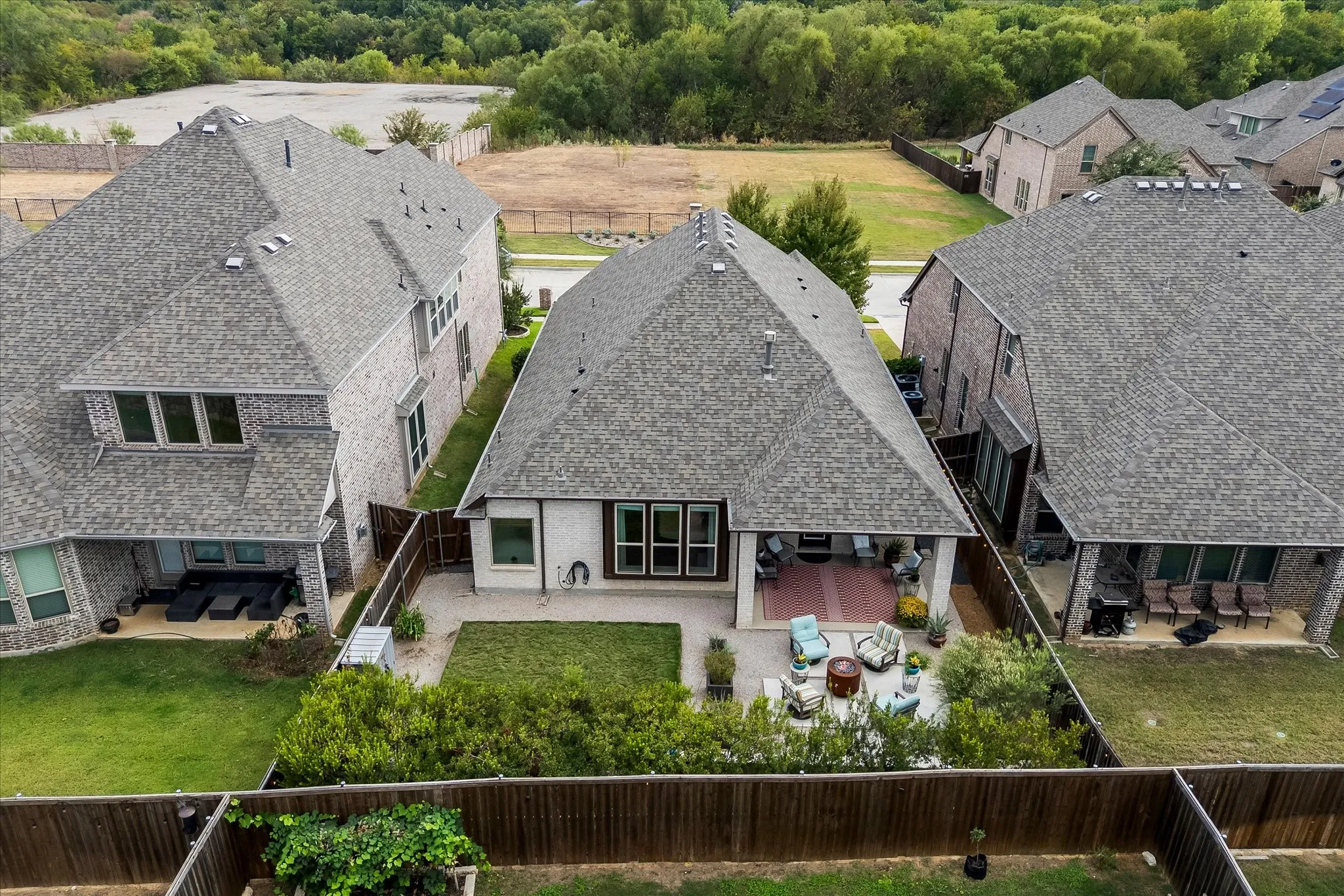 Expansive fenced backyard featuring a manicured lawn, paved patio, and covered outdoor living area