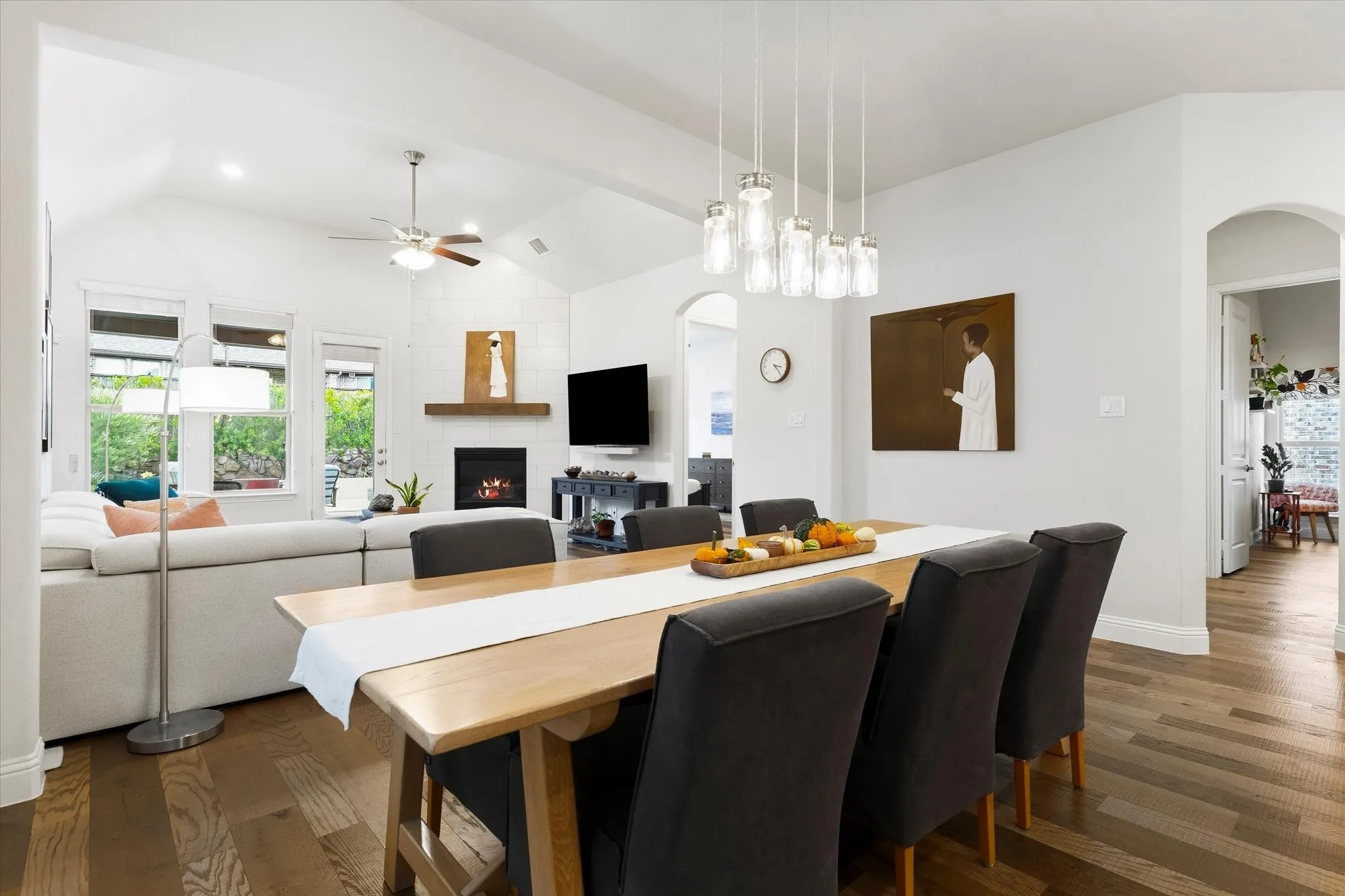 Vaulted ceilings, wood-finish flooring, a fireplace with a wood mantle, multiple windows, and recessed lighting